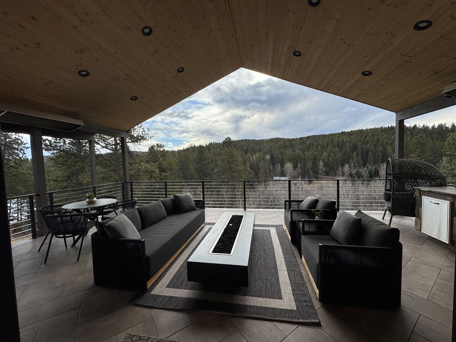 Panoramic view of a modern concrete structure with angular roof and glass walls overlooking a mountainous landscape.