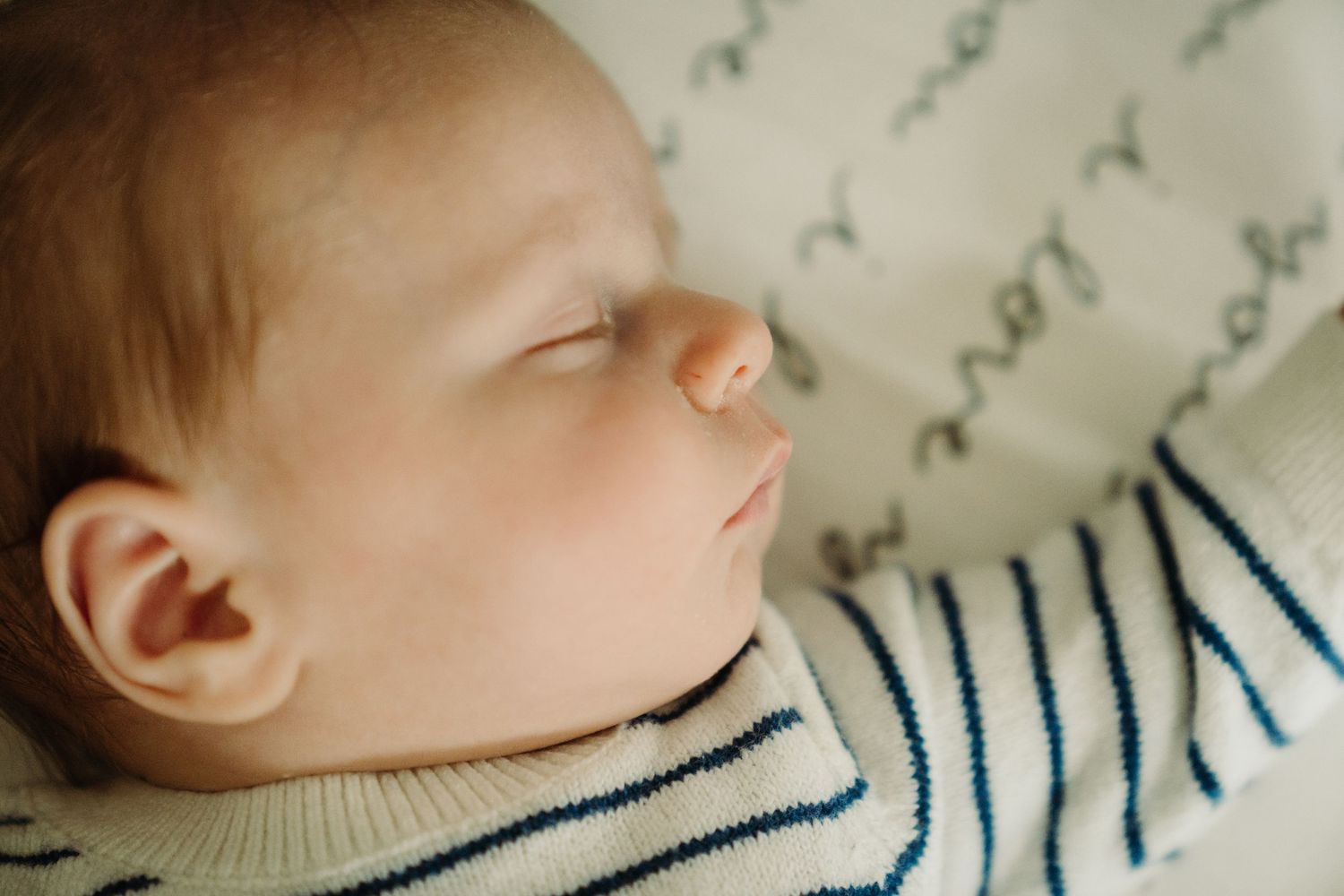 Close-up of sleeping baby wearing striped outfit with peaceful expression.