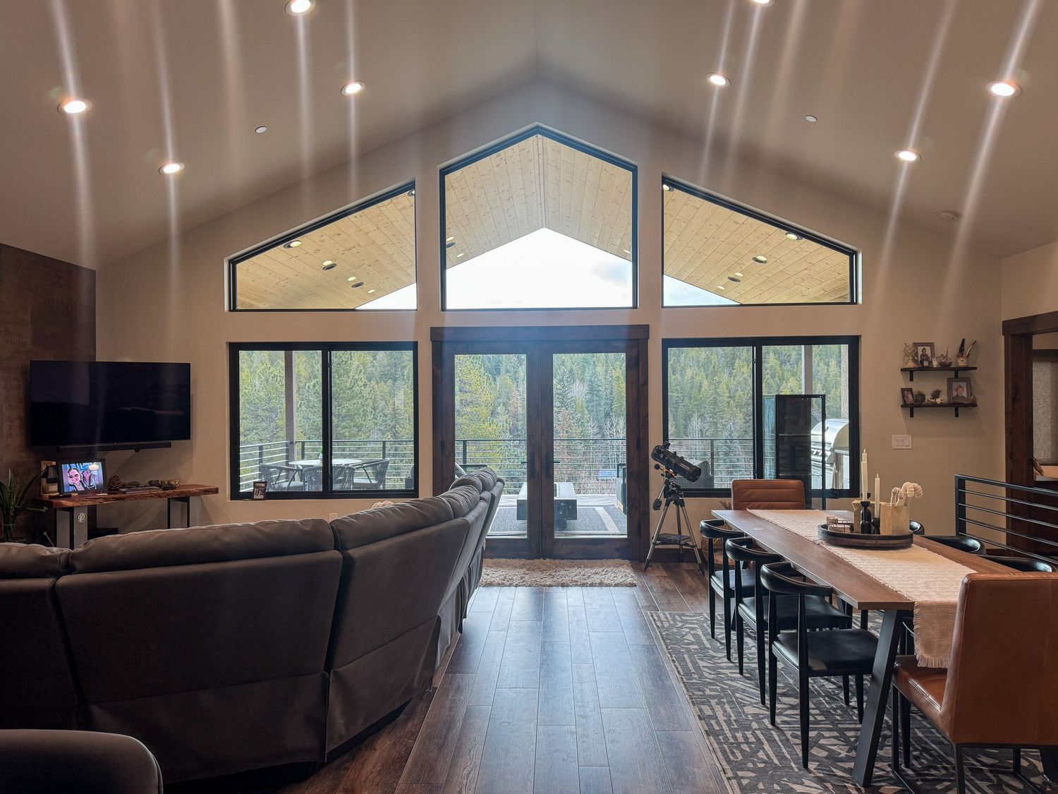 Modern open concept great room with vaulted ceilings, large windows, and contemporary furnishings in a luxury home.