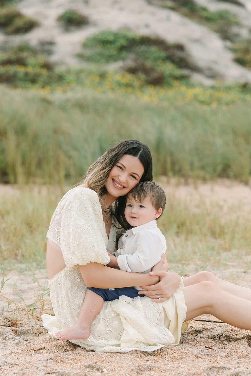 mom snuggling with toddler sun sitting in the sand at Ponte Vedra Beach