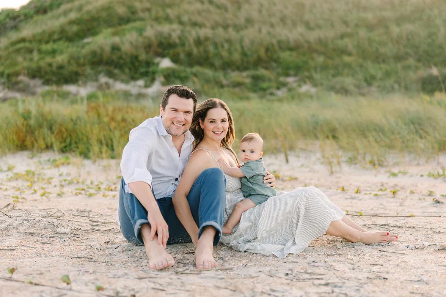 family sitting on the sand smiling in Ponte Vedra Beach fl dunes
