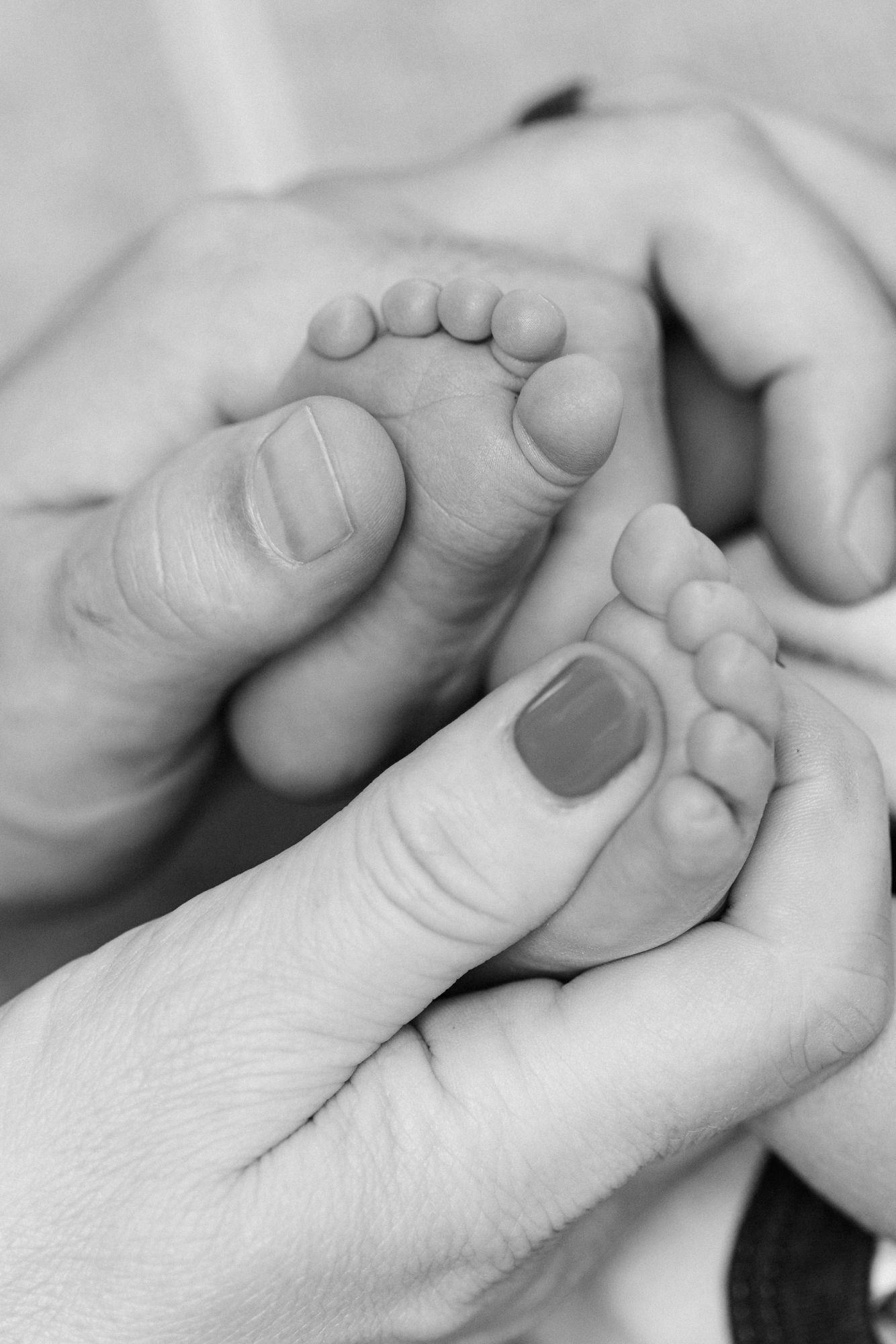 parents hands with newborn baby toes showing how tiny his feet are