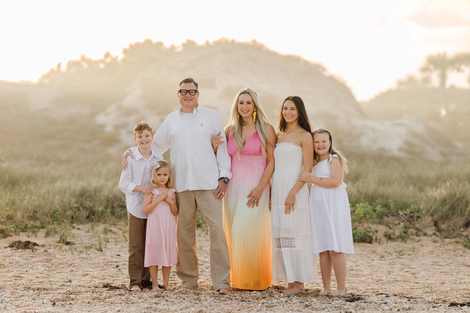 family at the beach at sunset with pink and white on