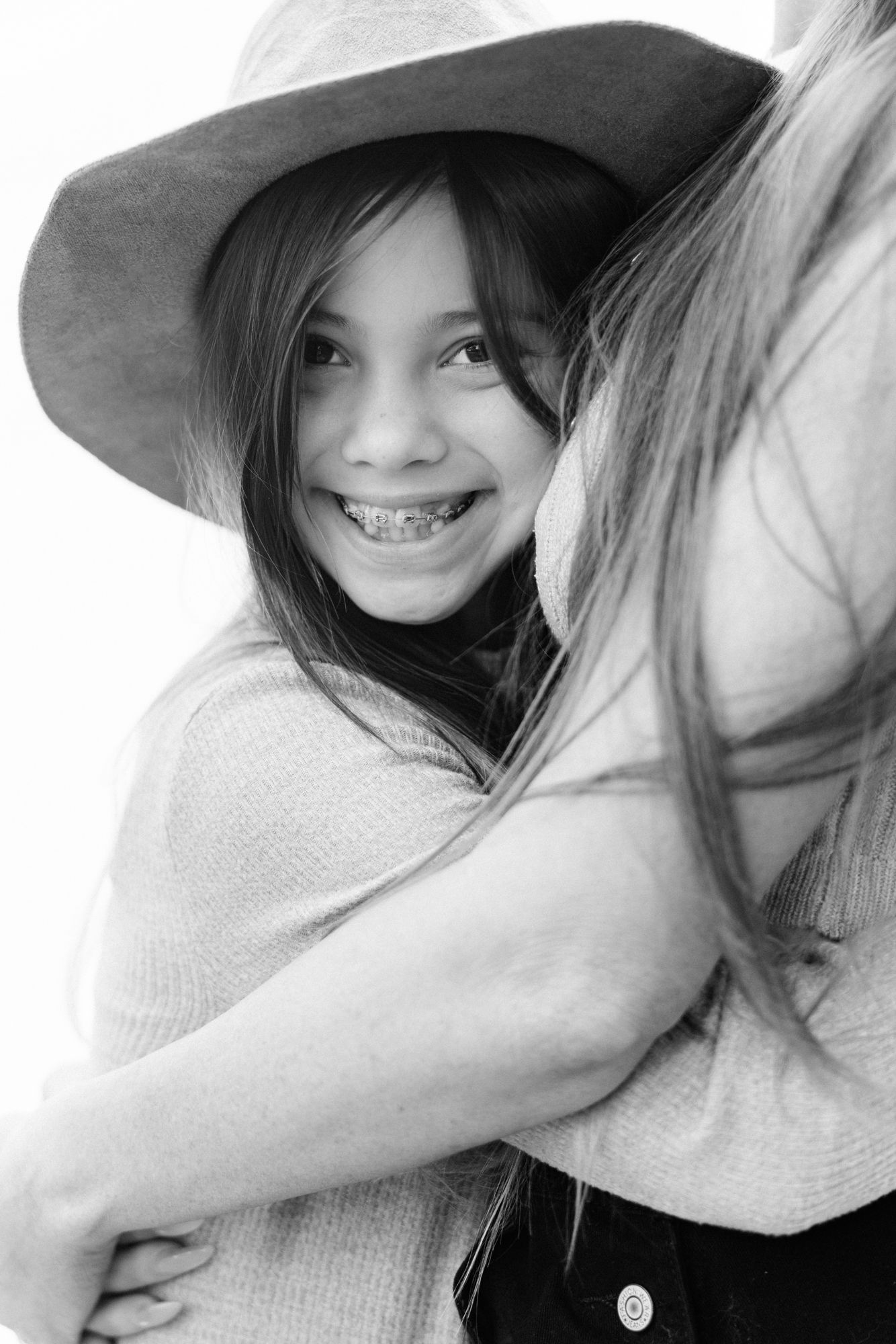 black and white of daughter smiling as she hugs mom