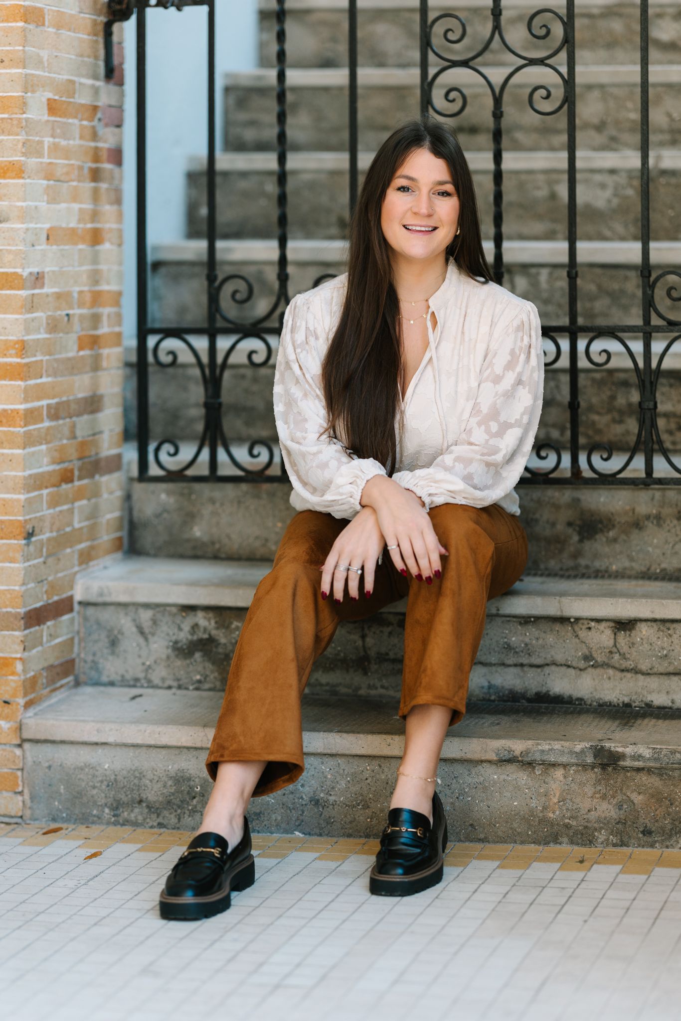 Caitlin Mae - your Jacksonville fl photographer - sitting on stairs in front of a gate