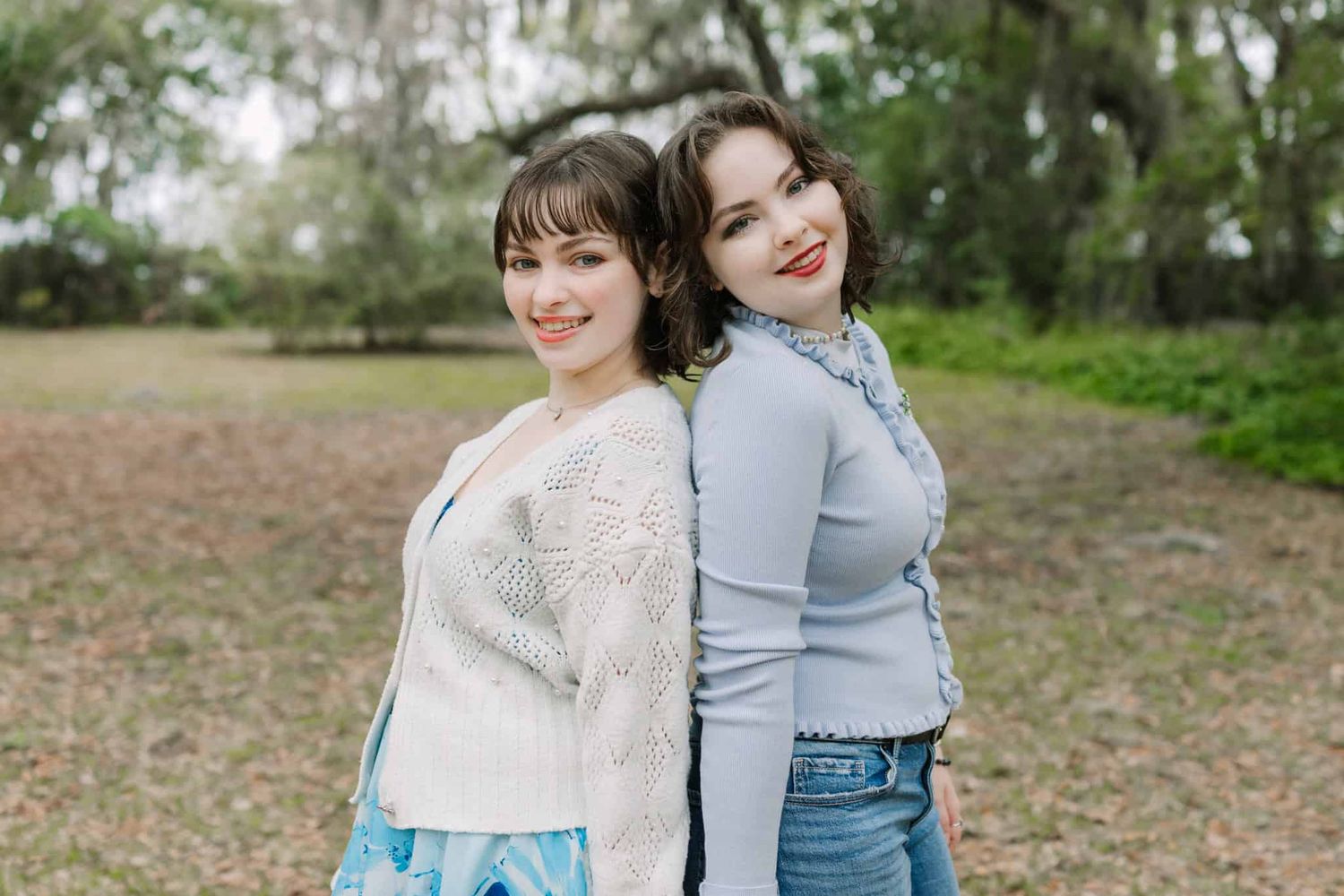 sisters back to back with heads together in the park