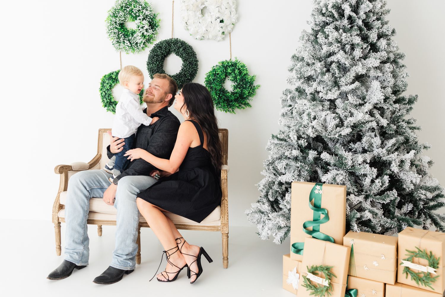 family laughing sitting on couch wearing black at Christmas setup photography session