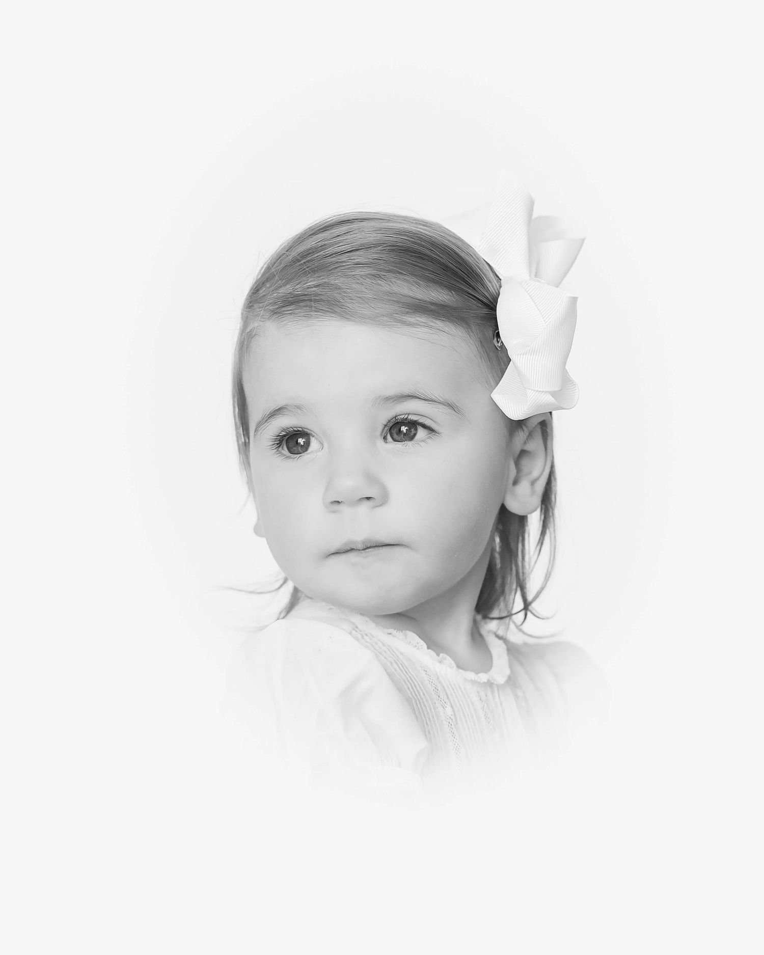 heirloom portrait of little girl with a bow looking back over her shoulder in black and white