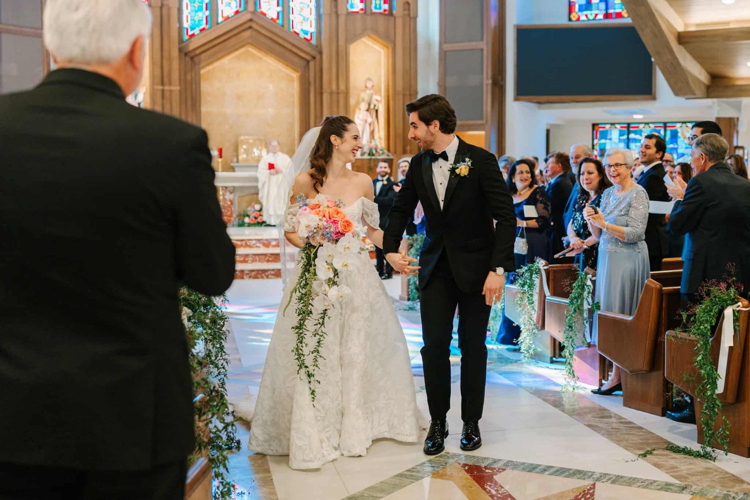bride and groom walking down the aisle during recession and smiling at each other
