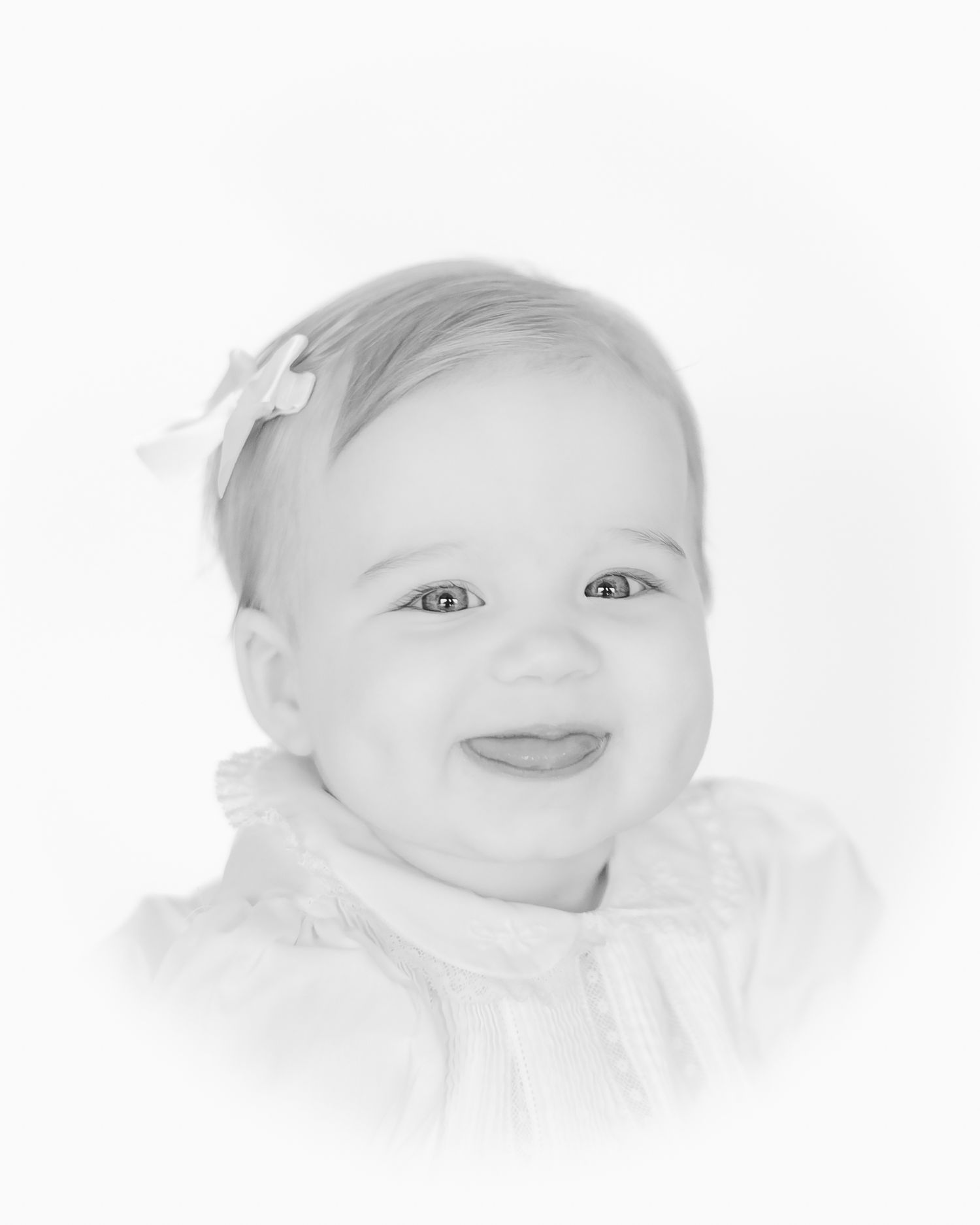 smiling baby girl with a bow heirloom portrait with her tongue sticking out