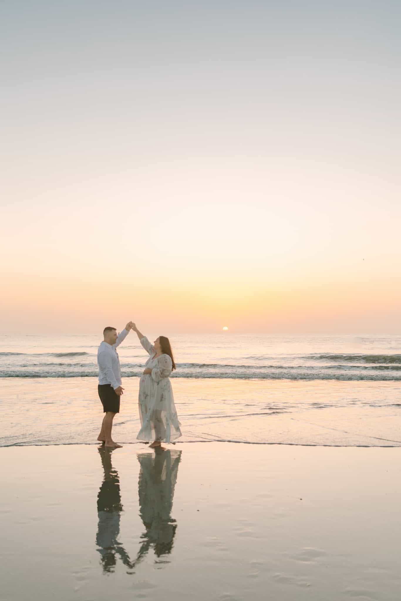 couple twirling at beach sunrise