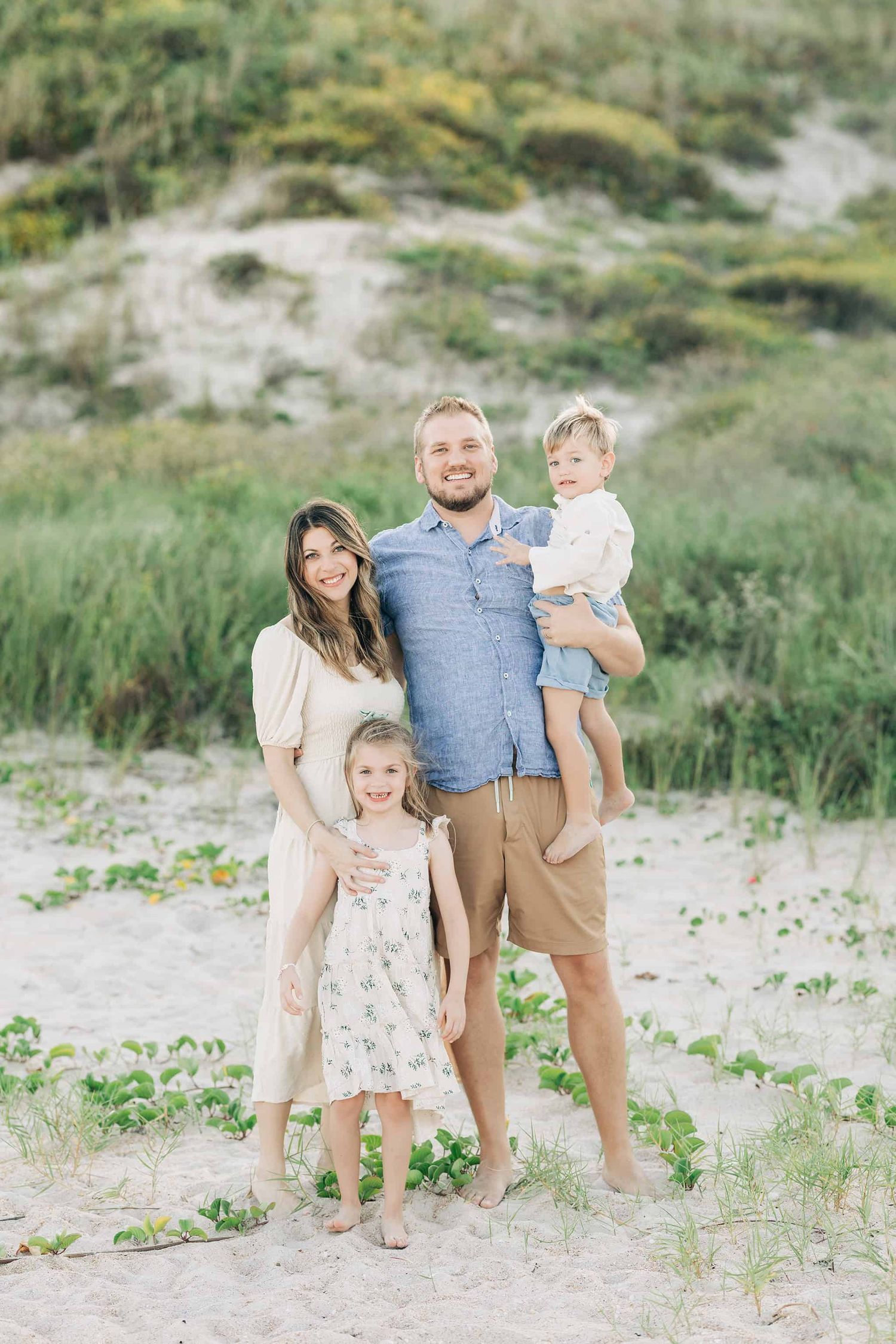 family standing in the sand in Jacksonville Beach fl with daughter and dad is holding son