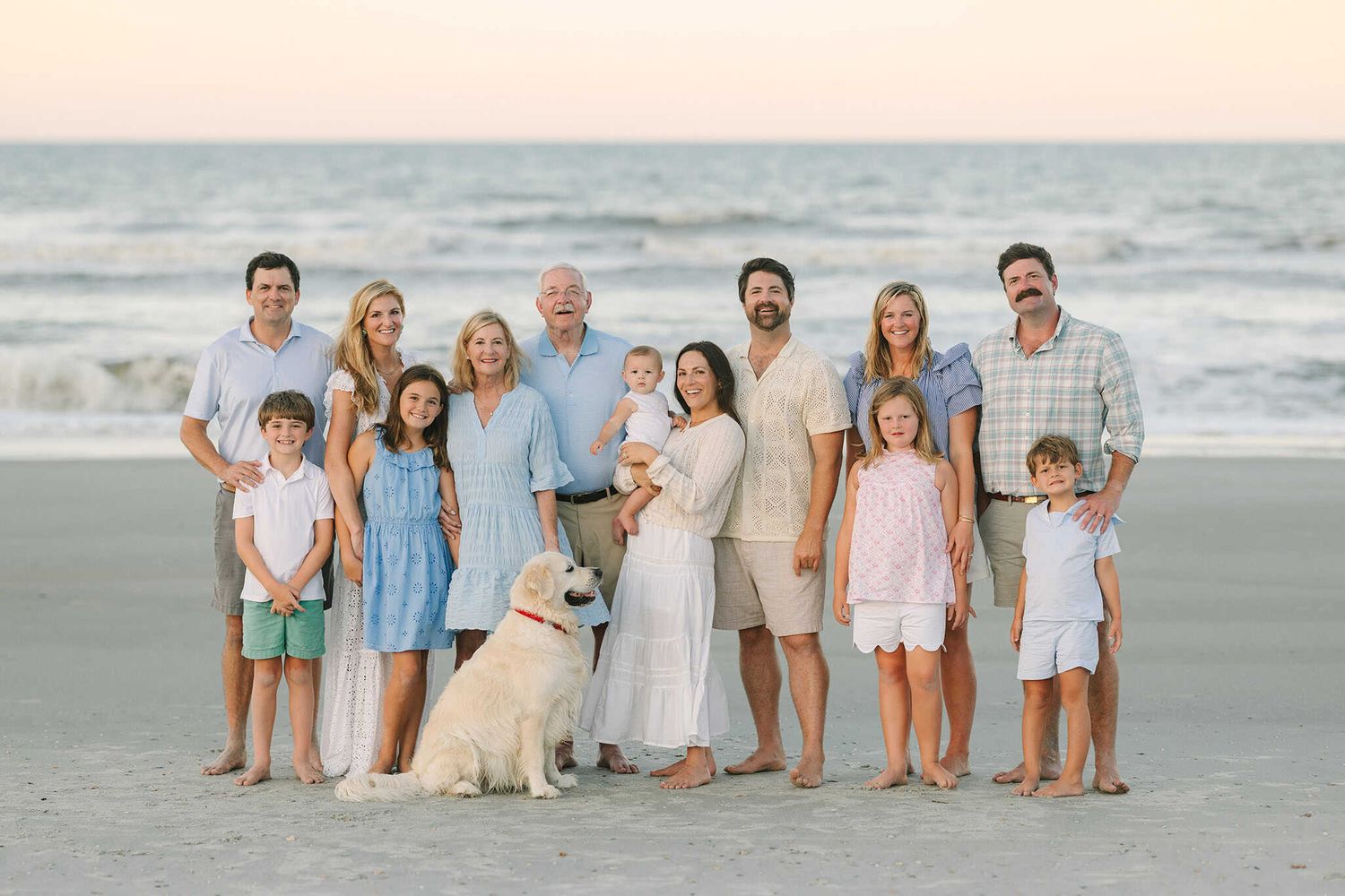 extended family at Jacksonville beach with the water in the back including their dog