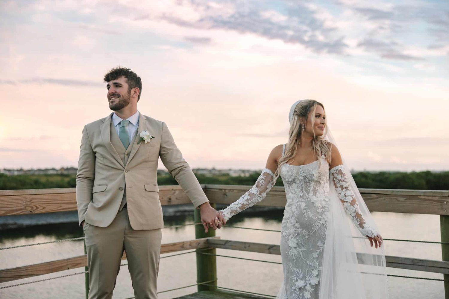 bride and groom holding hand looking away from each other during sunset