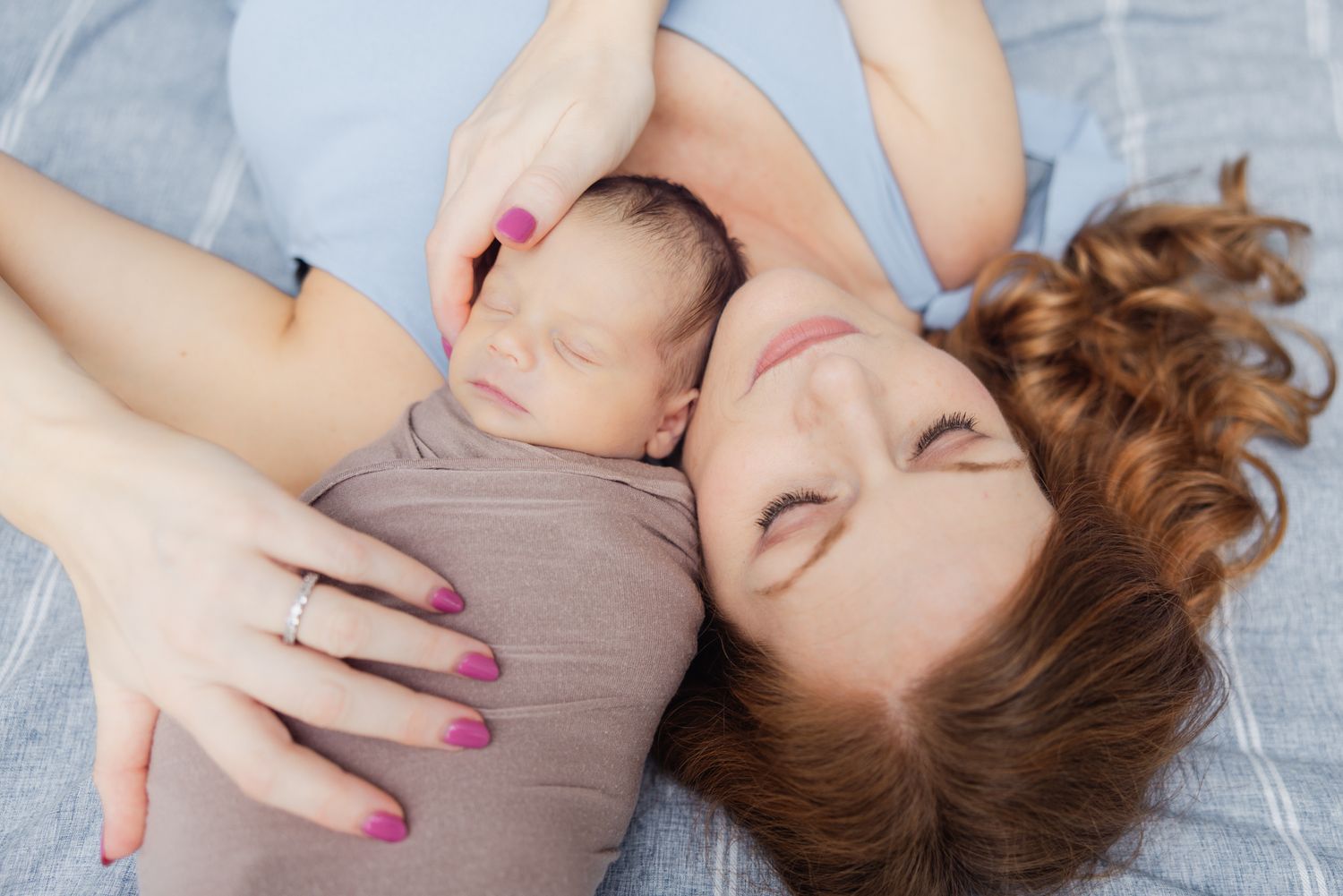newborn baby swaddled laying on mother's shoulder from above