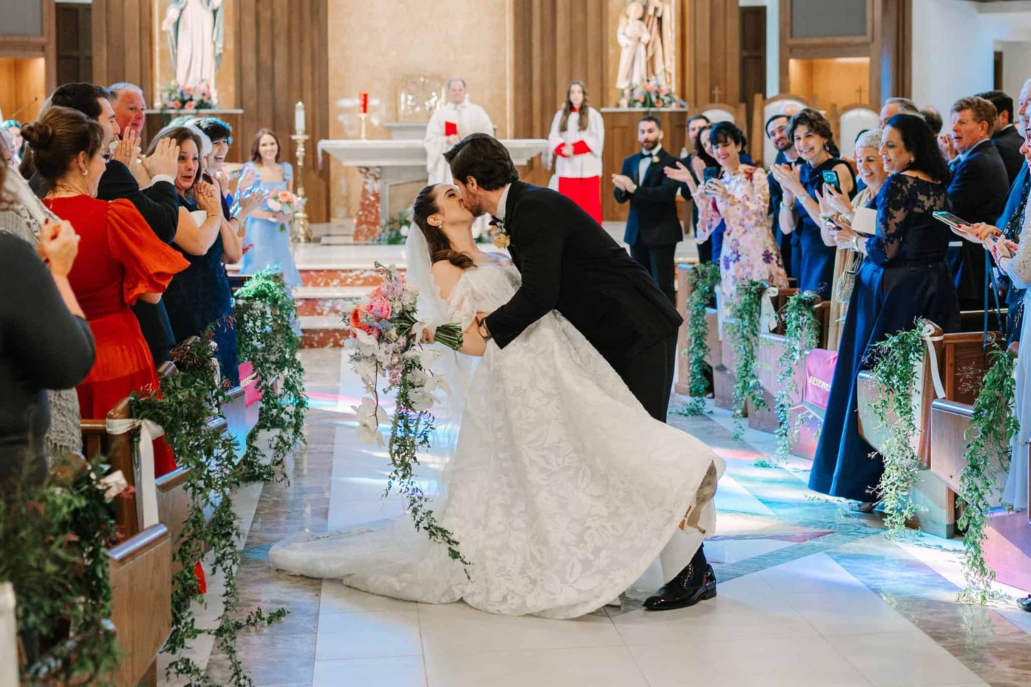 groom dipping bride for a kiss walking down the aisle after getting married in church