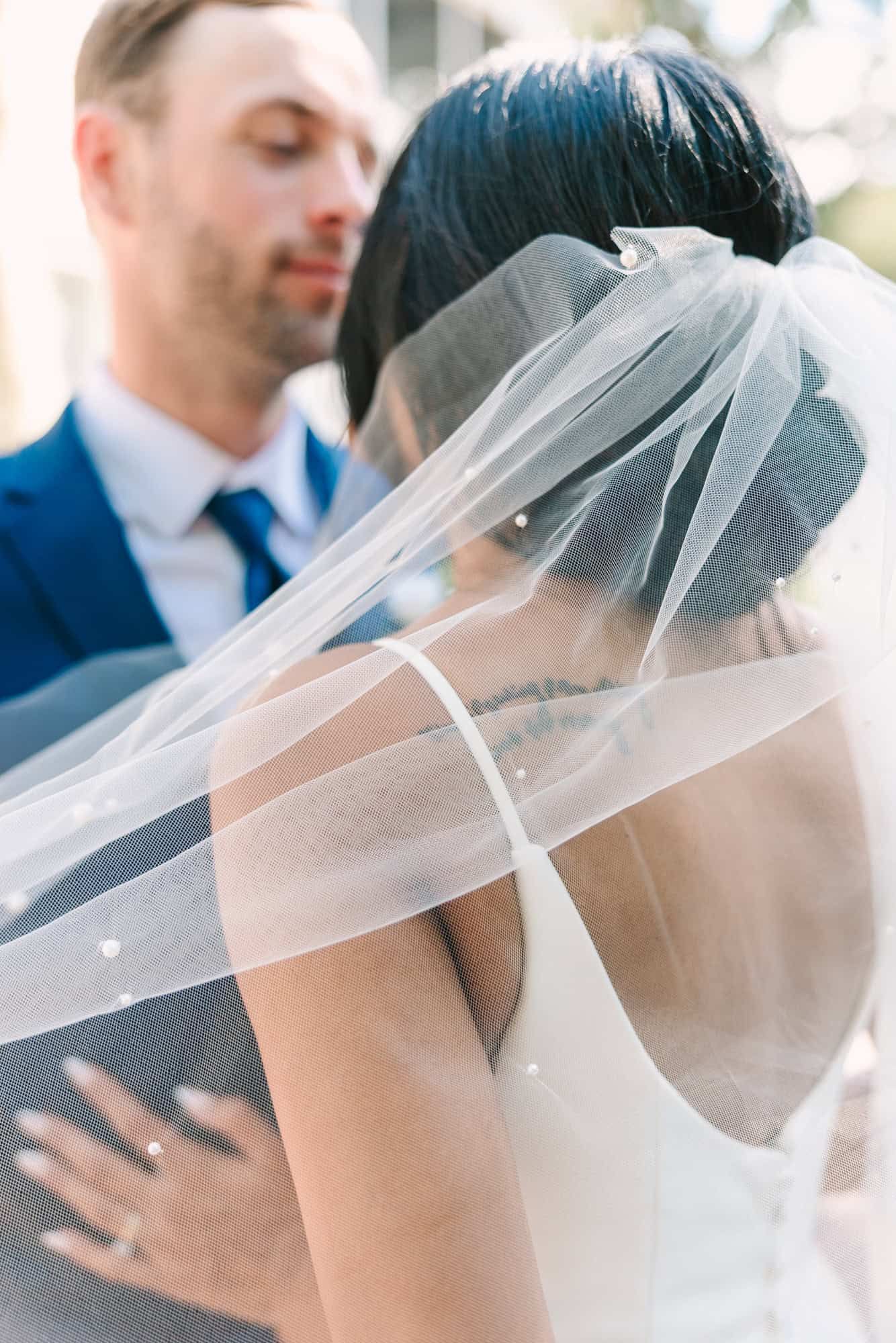 details of brides veil and ring as they look at each other