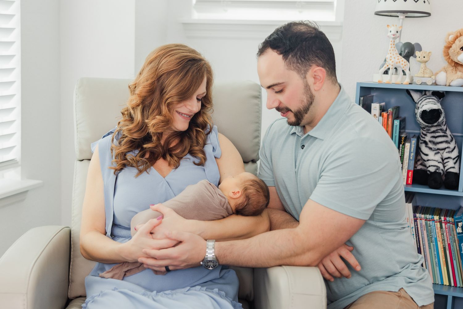 mom and dad smiling and admiring newborn baby in the nursery