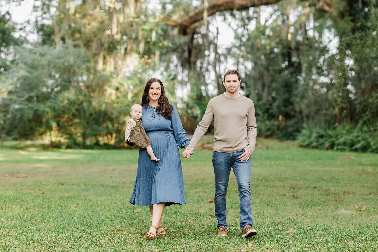 mom and dad walking in the park in Jacksonville fl with toddler girl on her hip