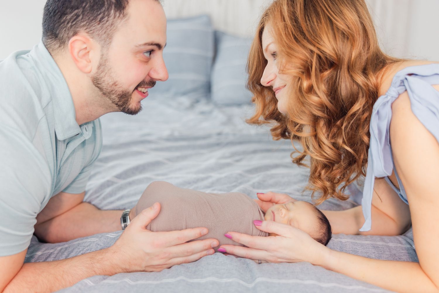 mom and dad looking at each other over newborn baby