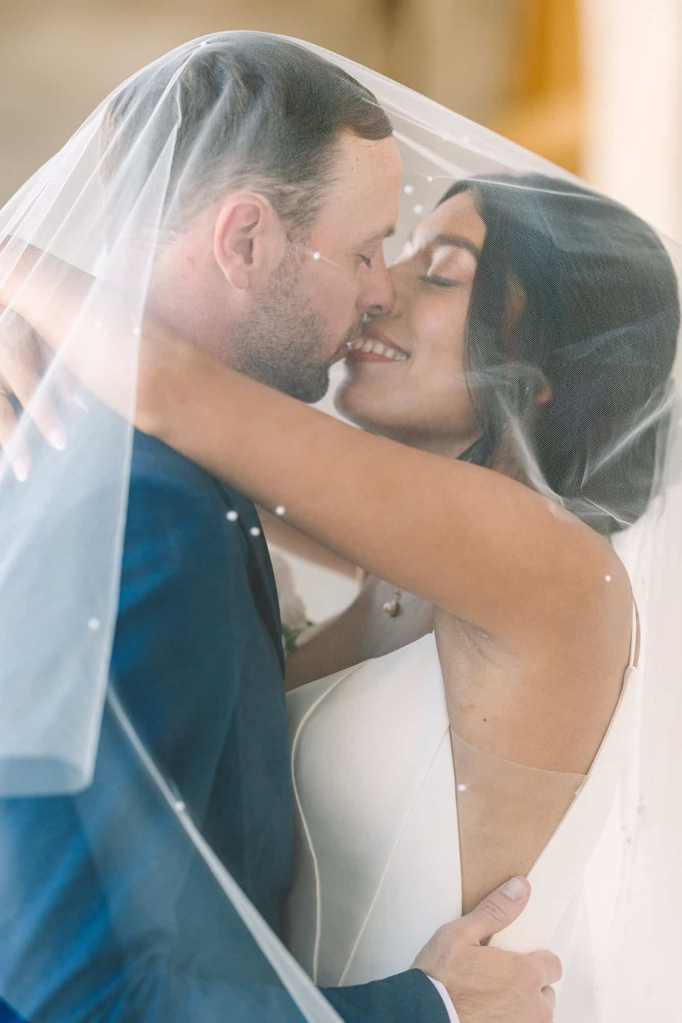 bride and groom kissing under her veil