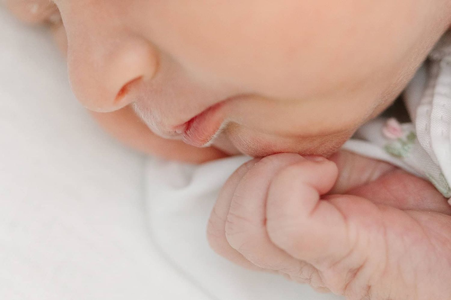 close up image of newborn baby's lips but her hand is up near her chin also