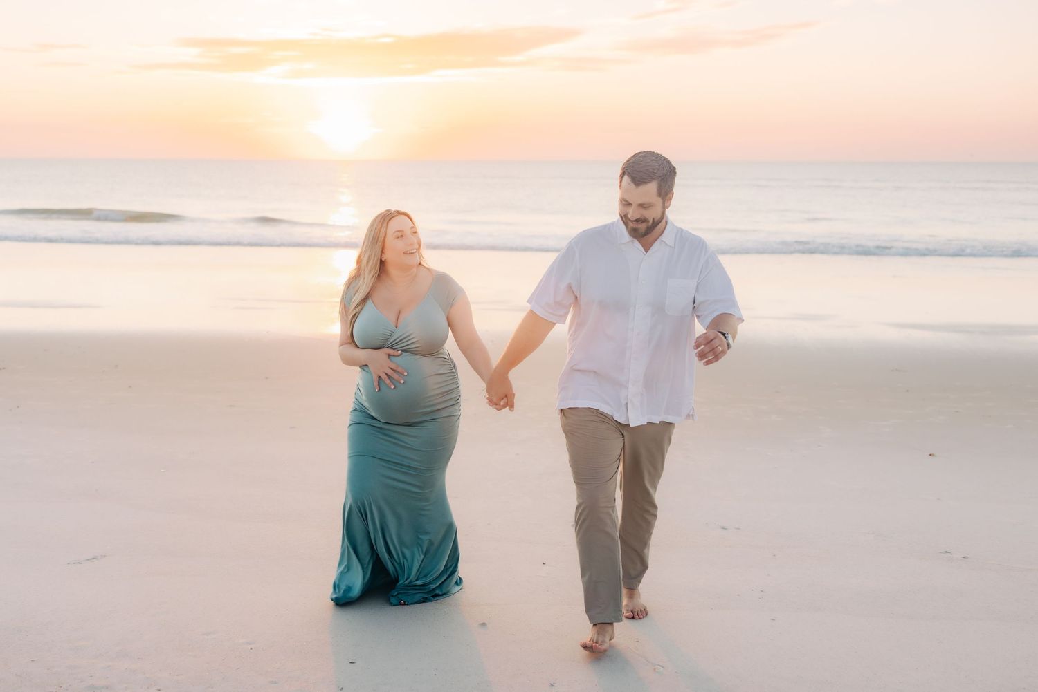 sunrise pregnant couple walking up the beach