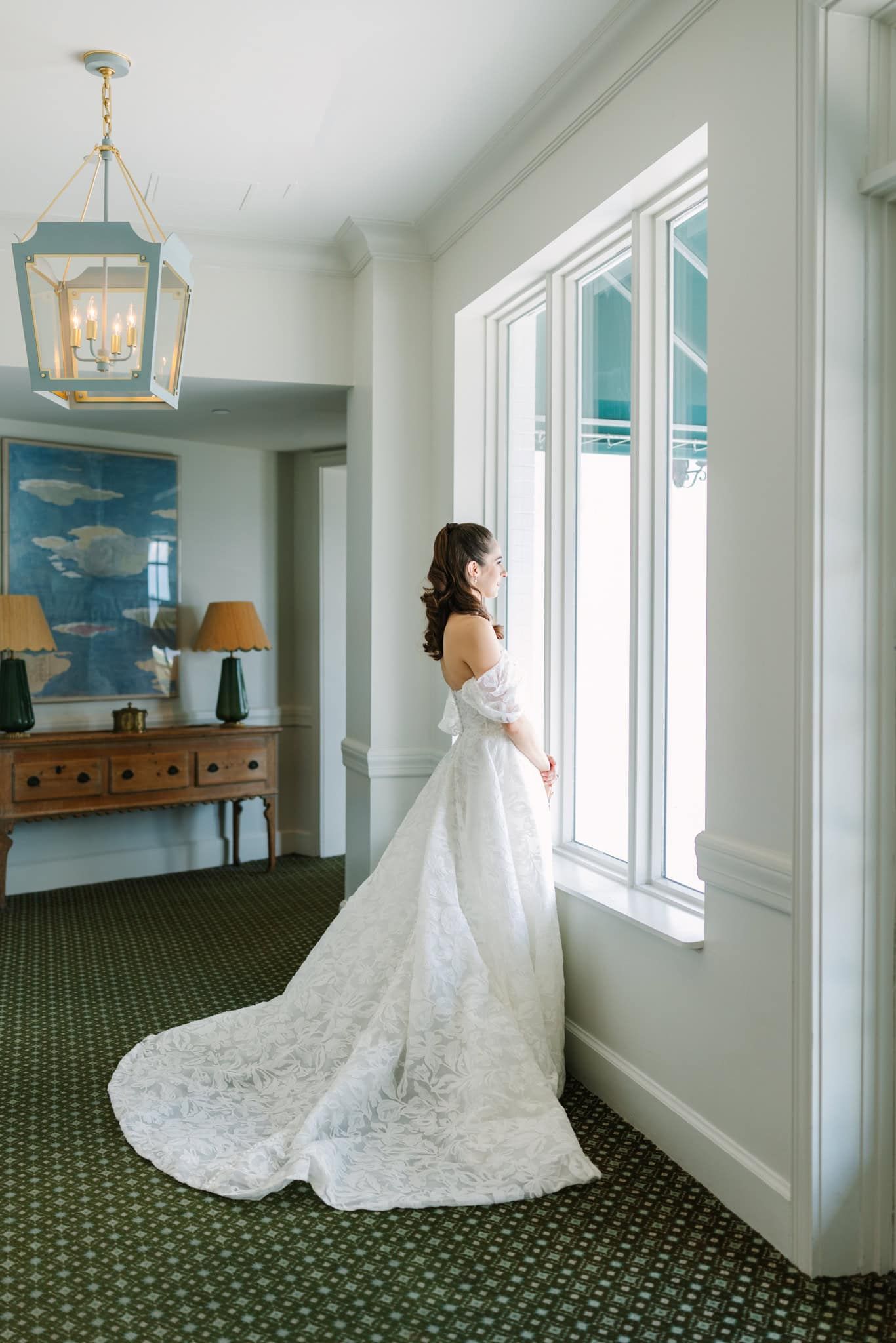 bride standing looking out the window dressed and ready for her wedding