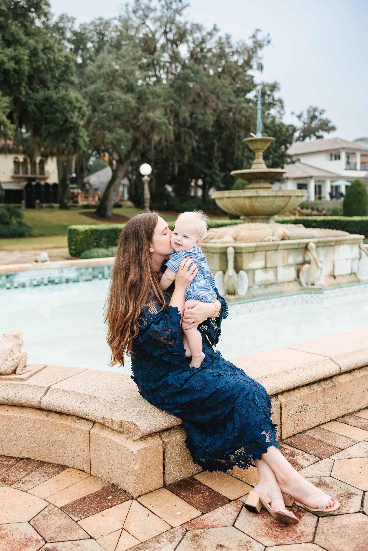 mom holding toddler boy sitting near a fountain at epping forest