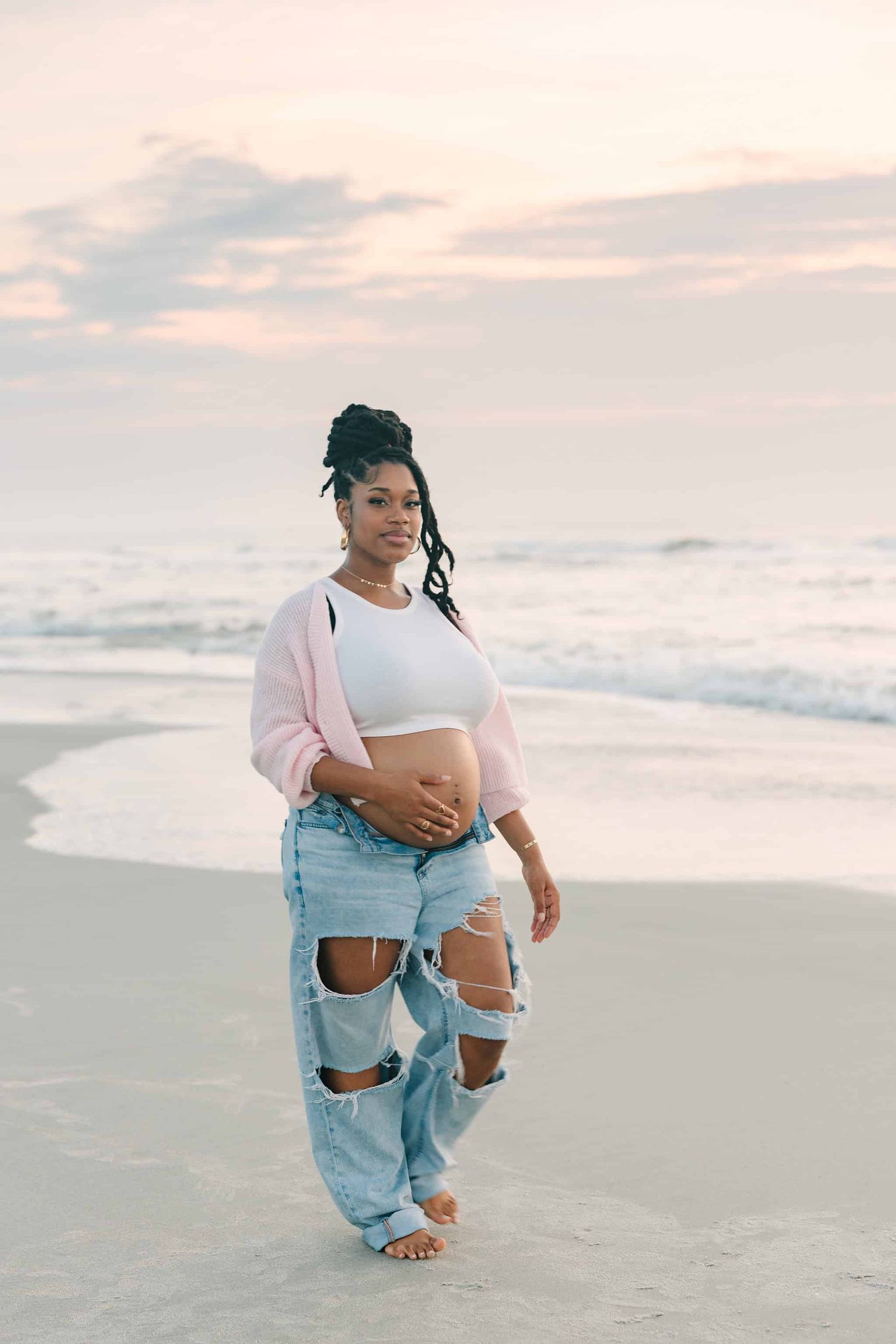 pregnant mom walking down jacksonville beach with her belly out at sunrise