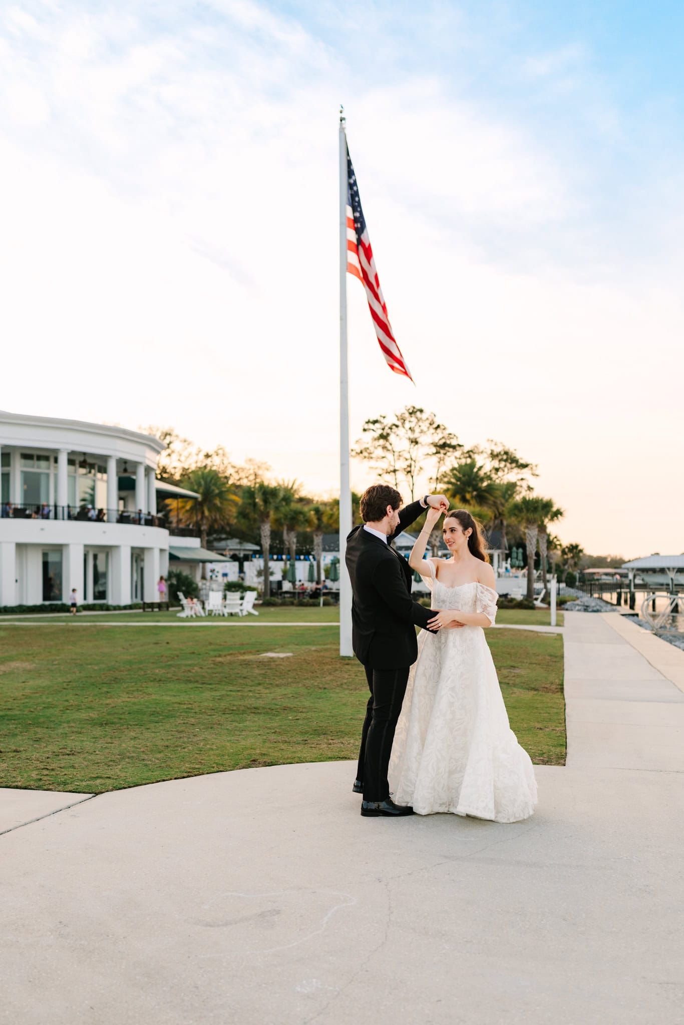 bride and groom dancing with american flag behind them