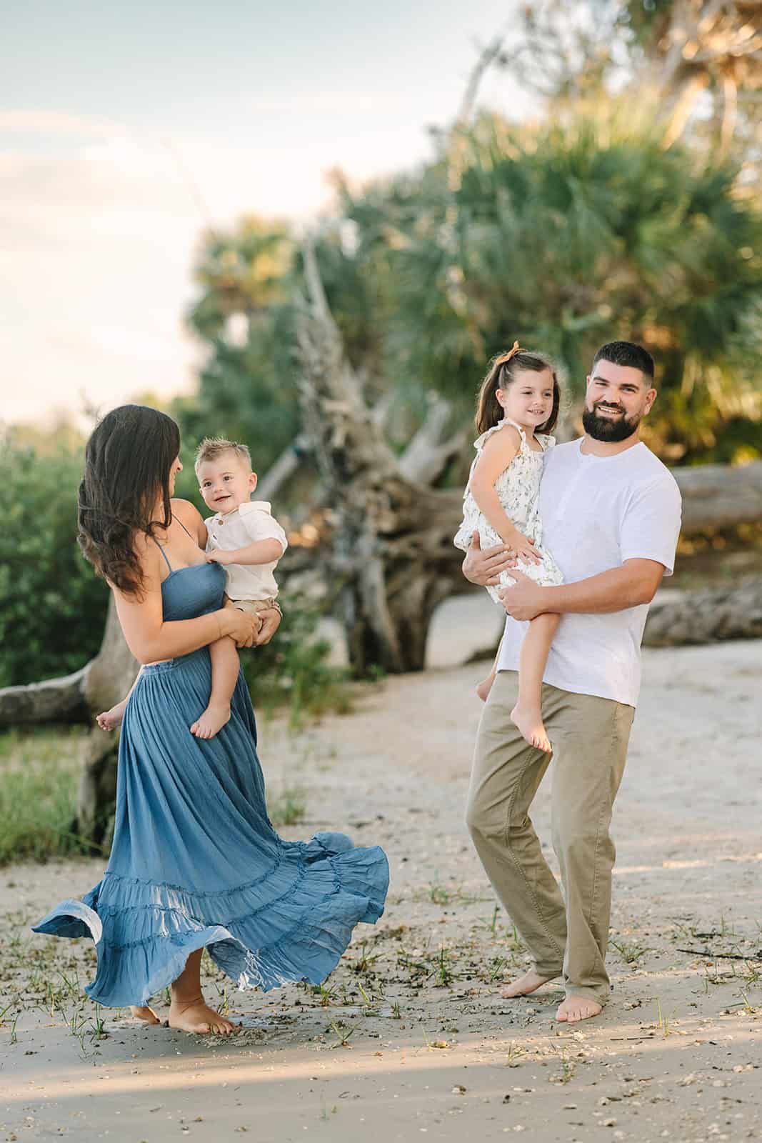 mom twirling holding son while her Dress spins and dad holding older daughter laughing