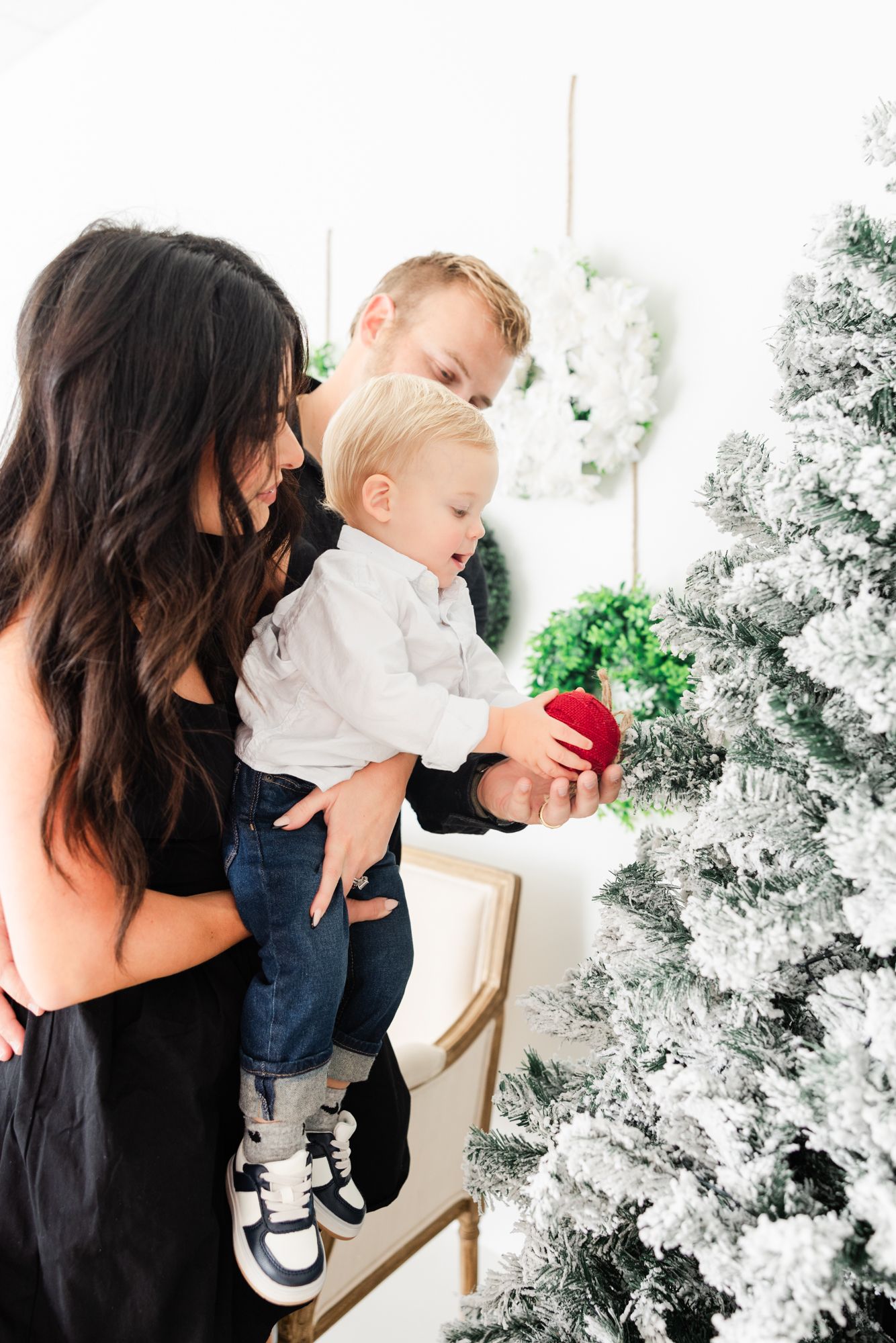 little boy putting ornament on Christmas tree