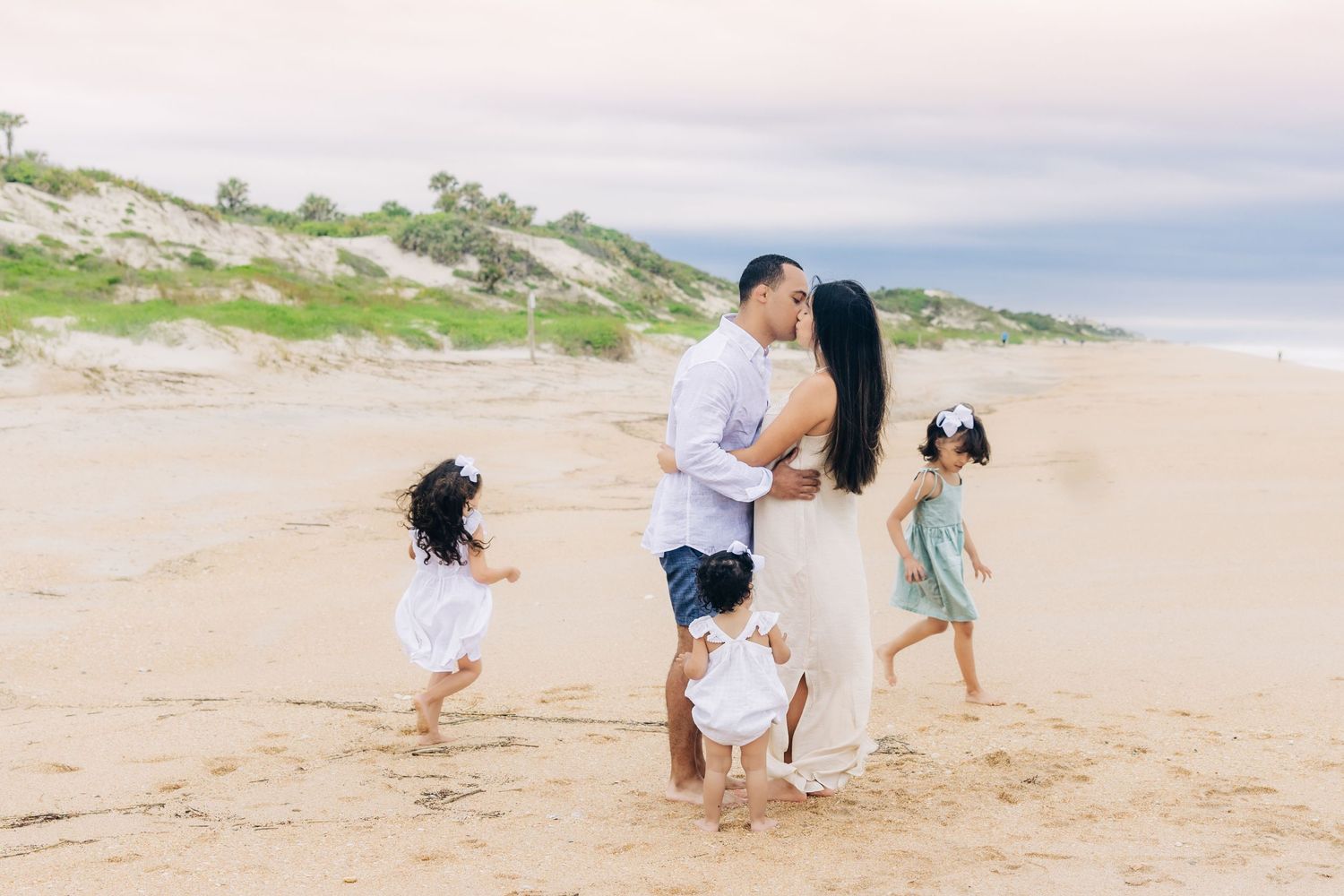 3 daughters running around parents on the beach