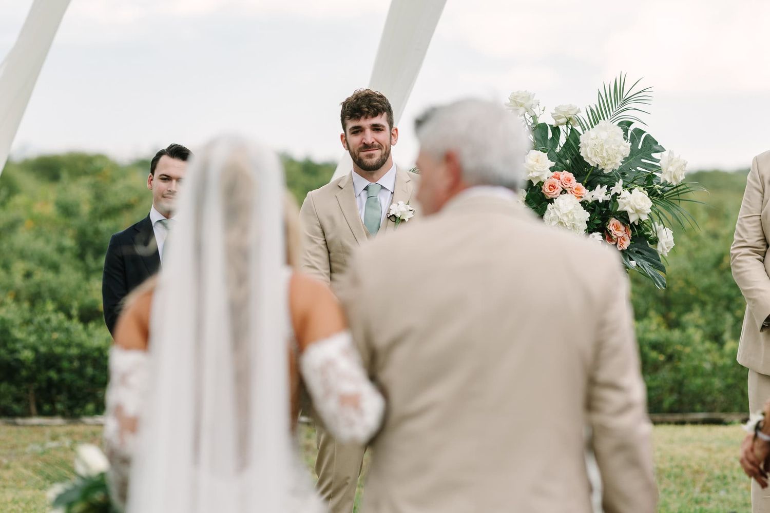 groom looking lovingly at his bride as she walks down the aisle