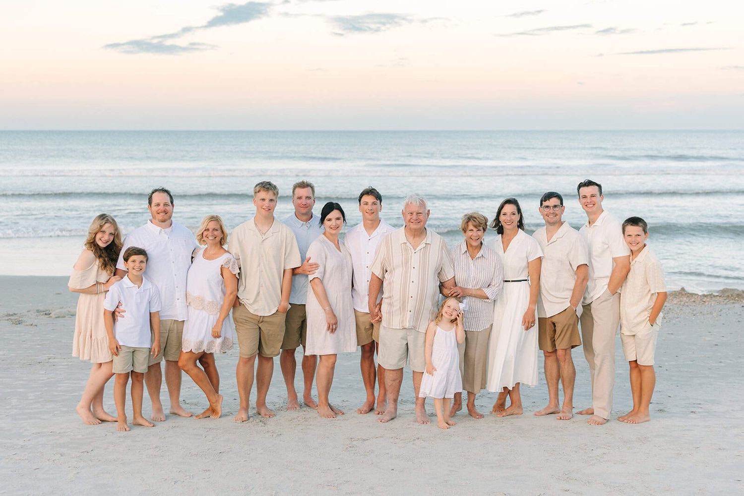 large extended family wearing all white and beige at Jacksonville beach sunset