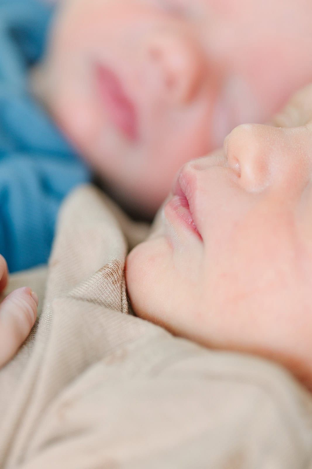 close up of newborn lips with twin brother laying behind him but out of focus