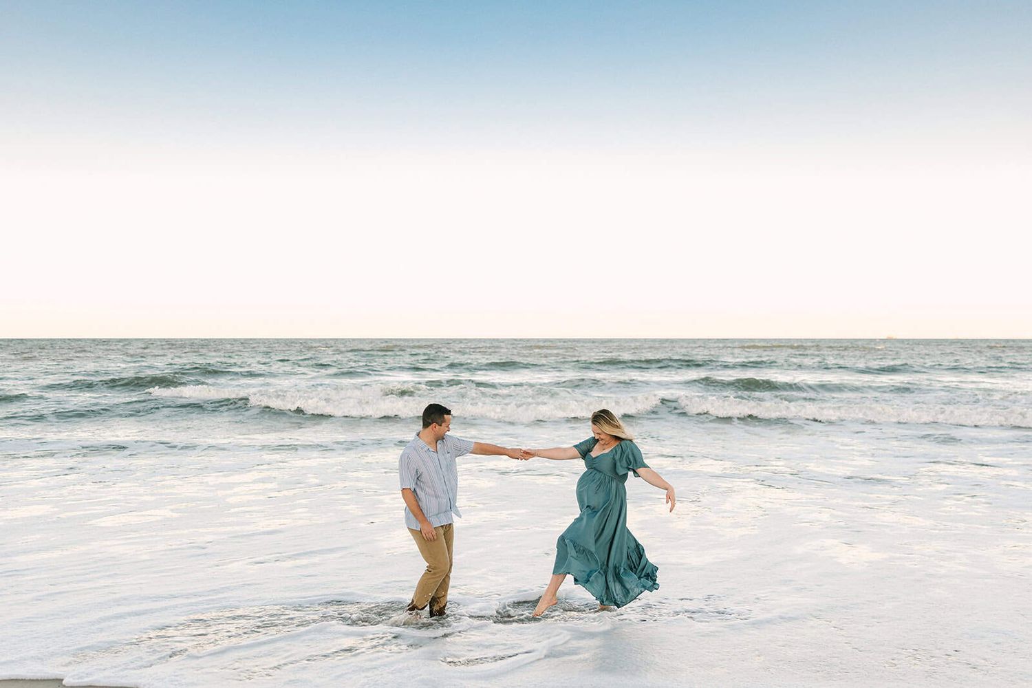 maternity couple playing in the ocean water