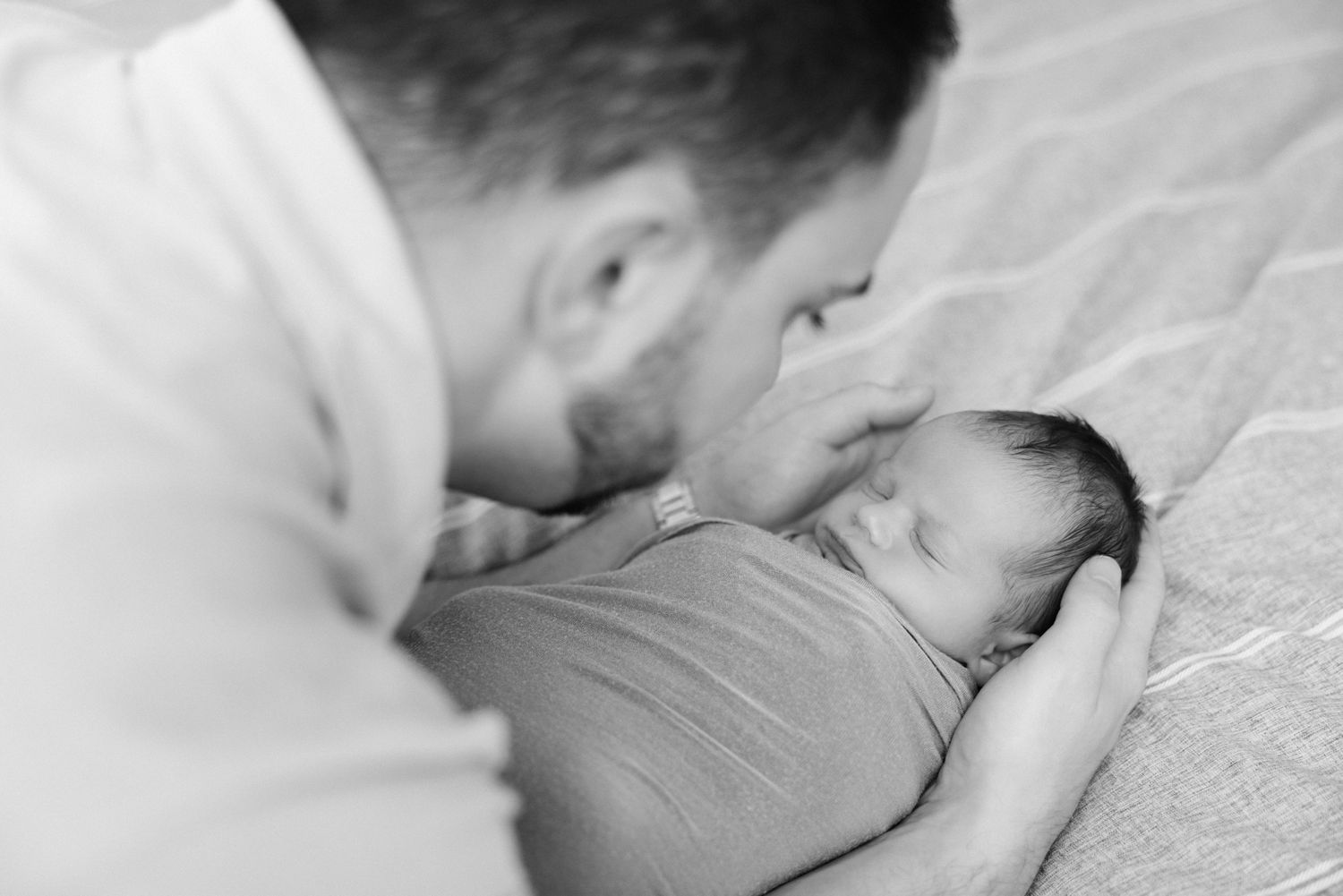 black and white photo of dad snuggling newborn baby