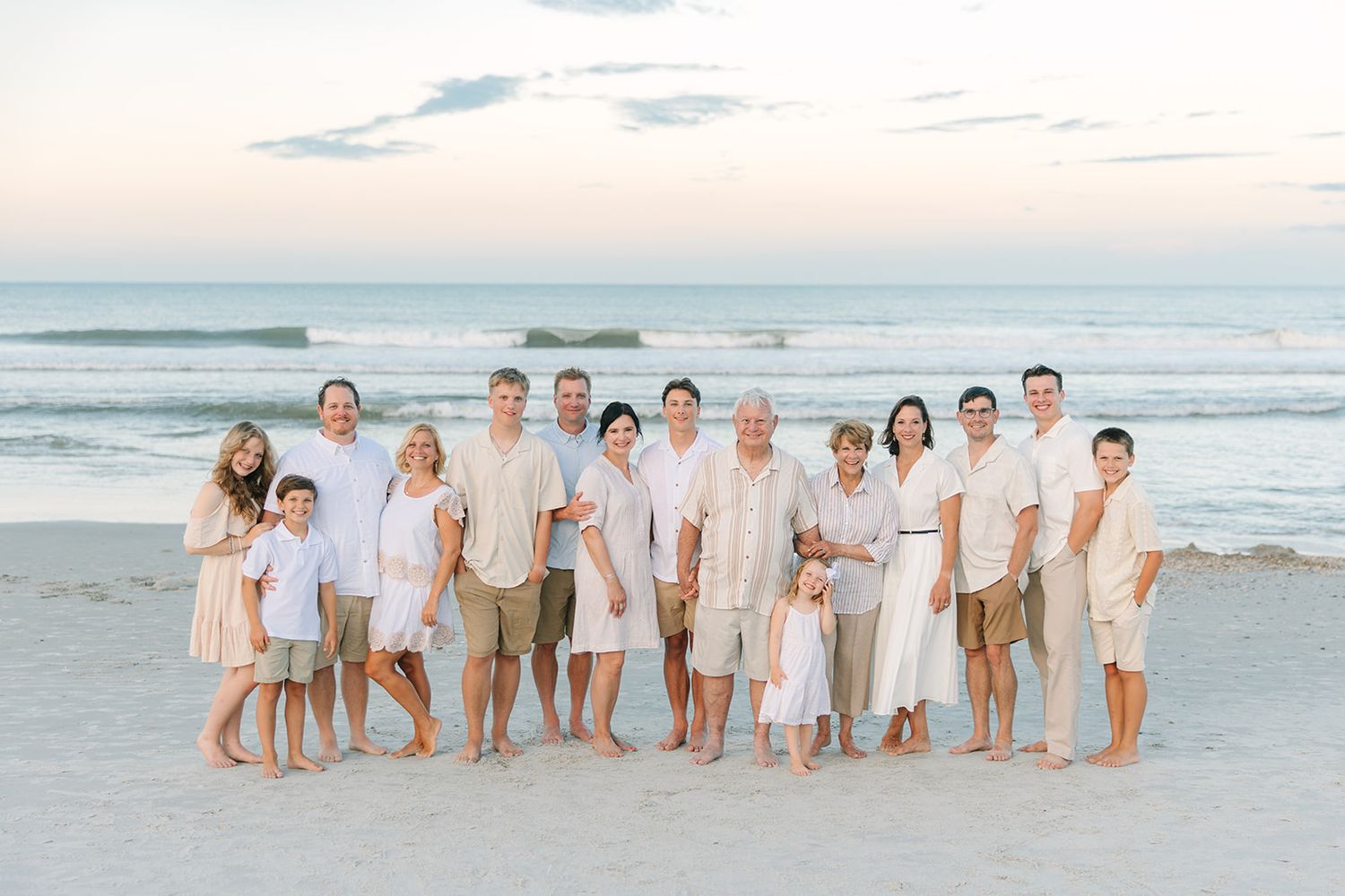 extended family of fifteen people at Jacksonville beach sunset all dressed in white