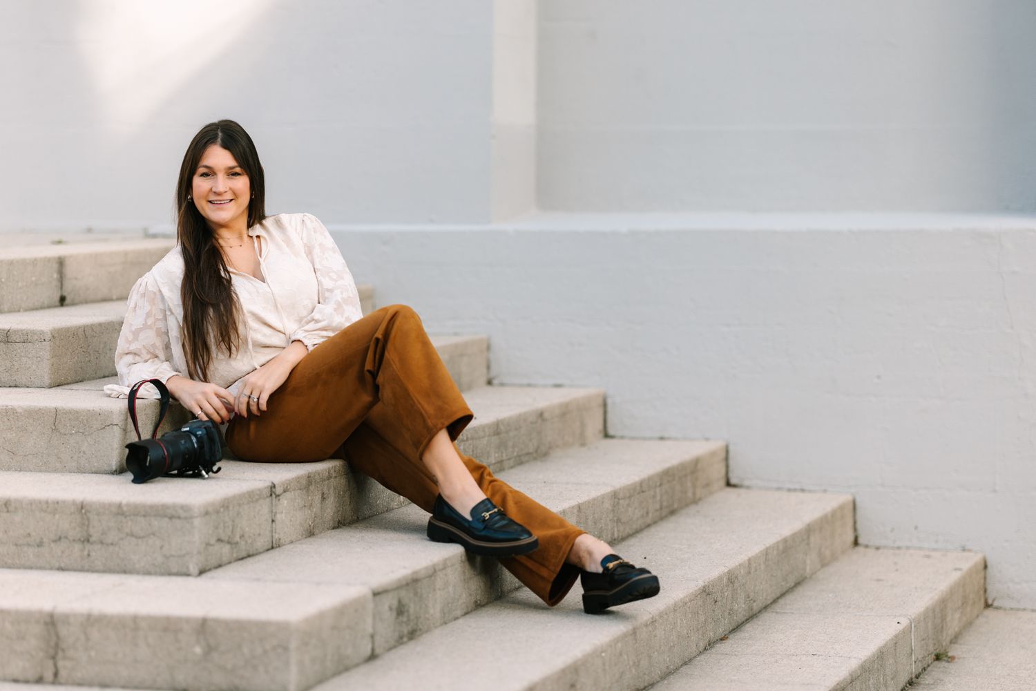 Caitlin mae sitting on some stairs with her camera