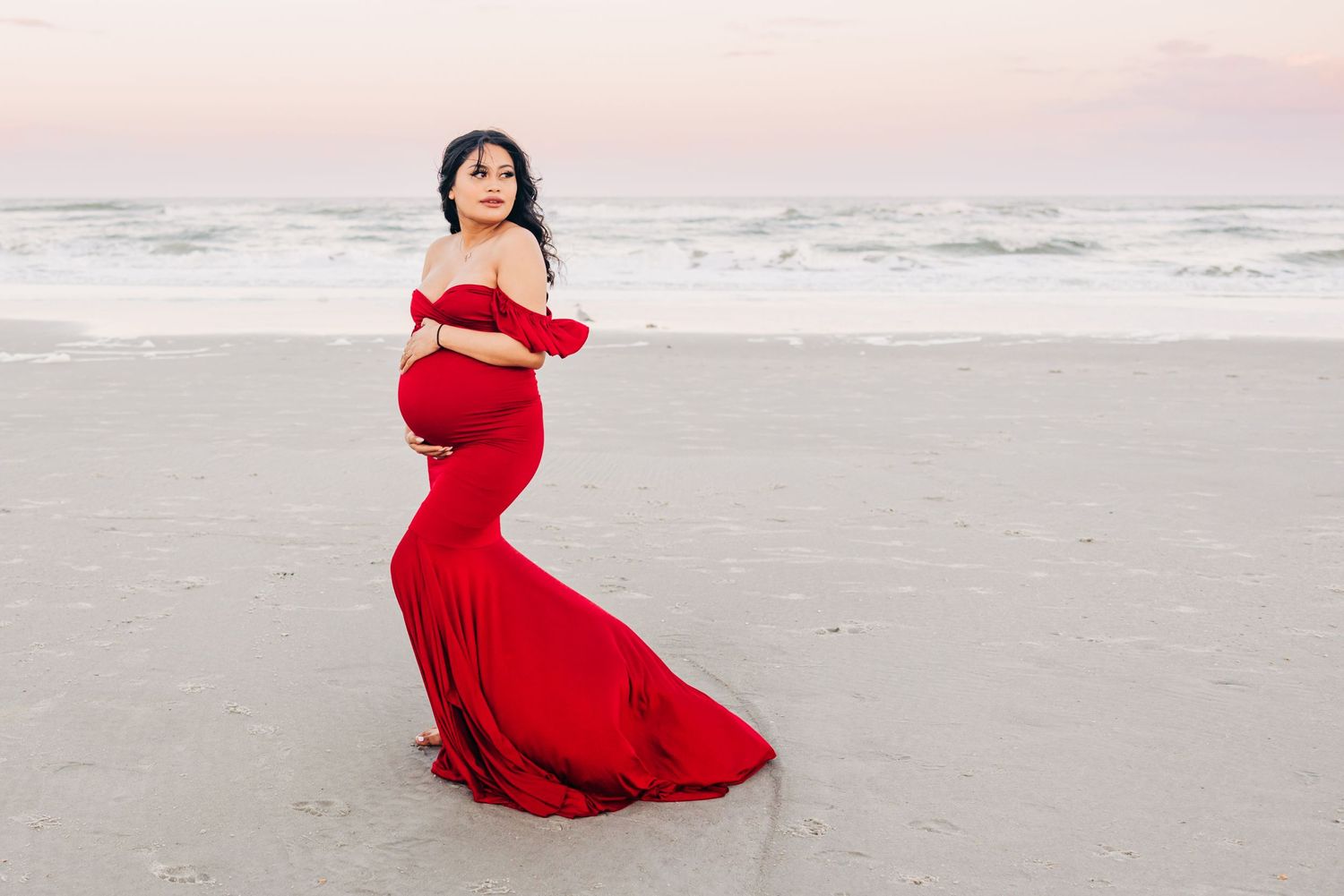 beautiful pregnant woman on jacksonville beach at sunset with a pretty red dress