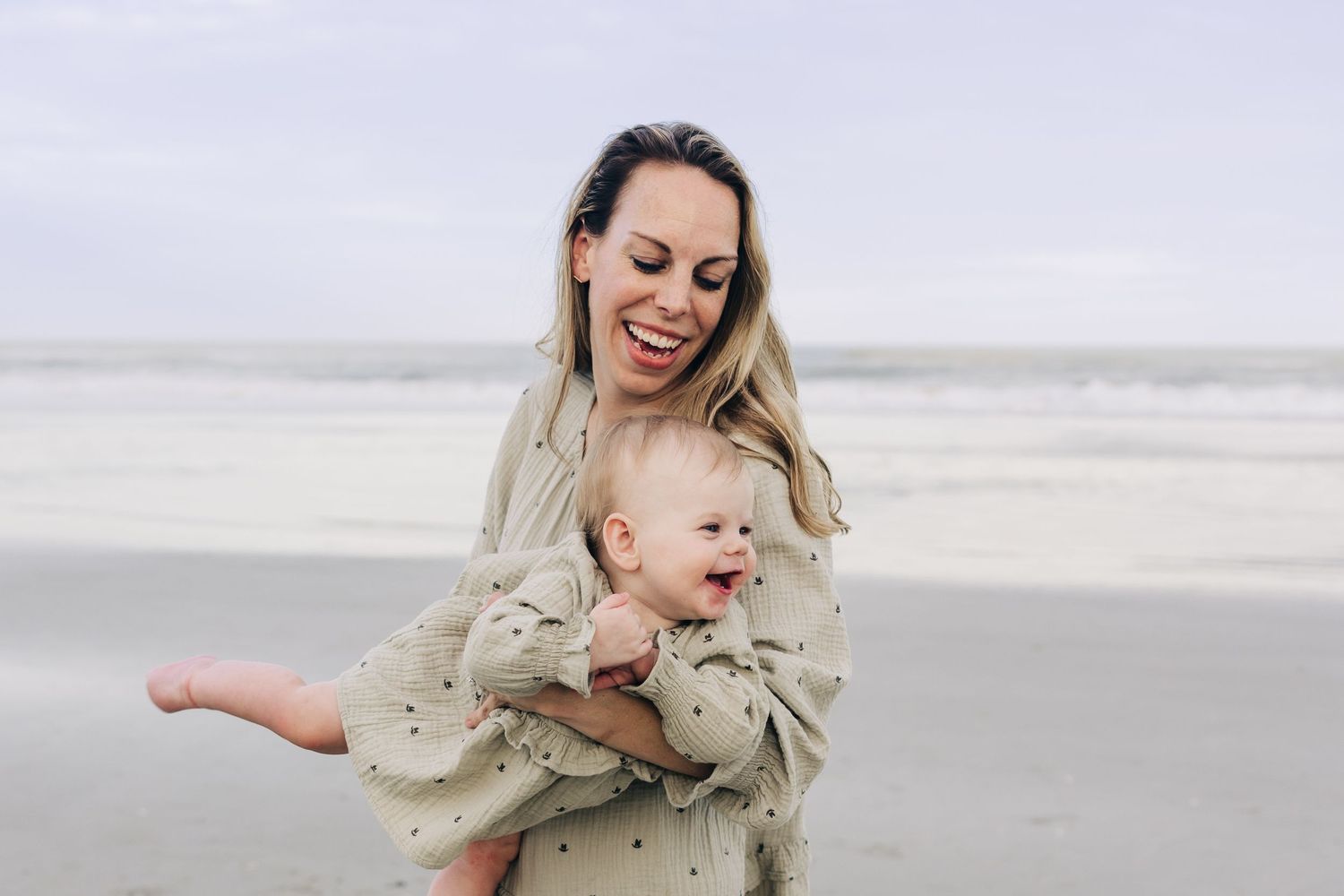 jacksonville fl photographer mom playing with daughter on the beach laughing in matching green dress