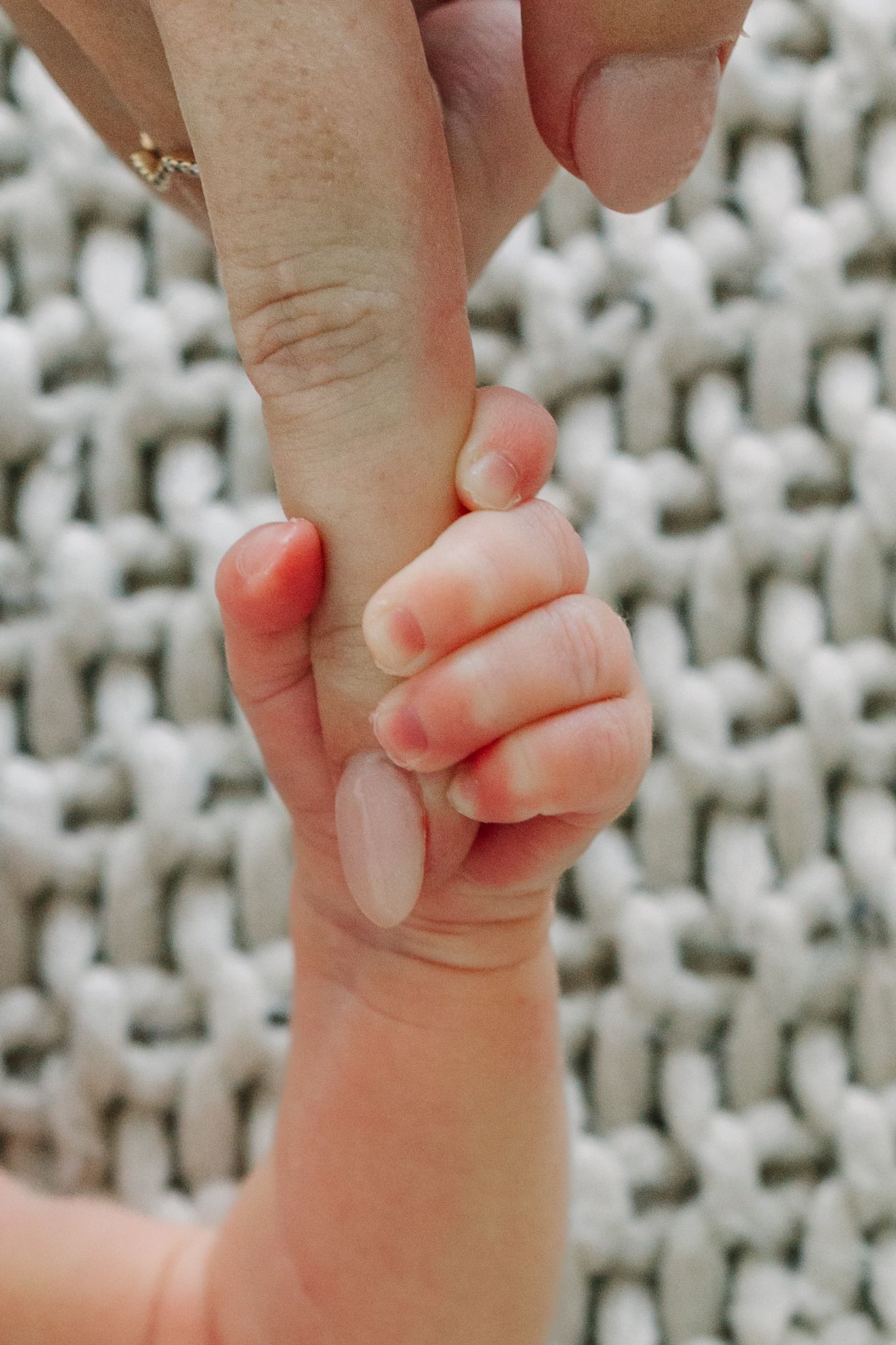 A baby's tiny hand gripping mom's finger, symbolizing trust and the bond between mother and child.