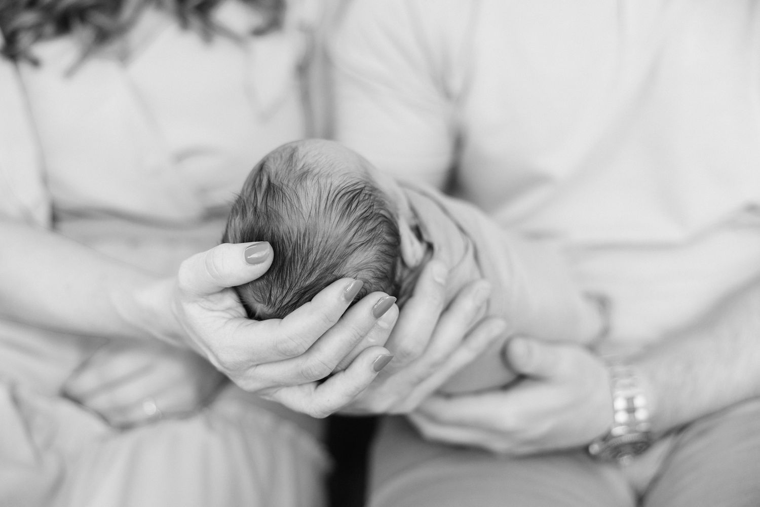 black and white photo of hands holding baby head from above
