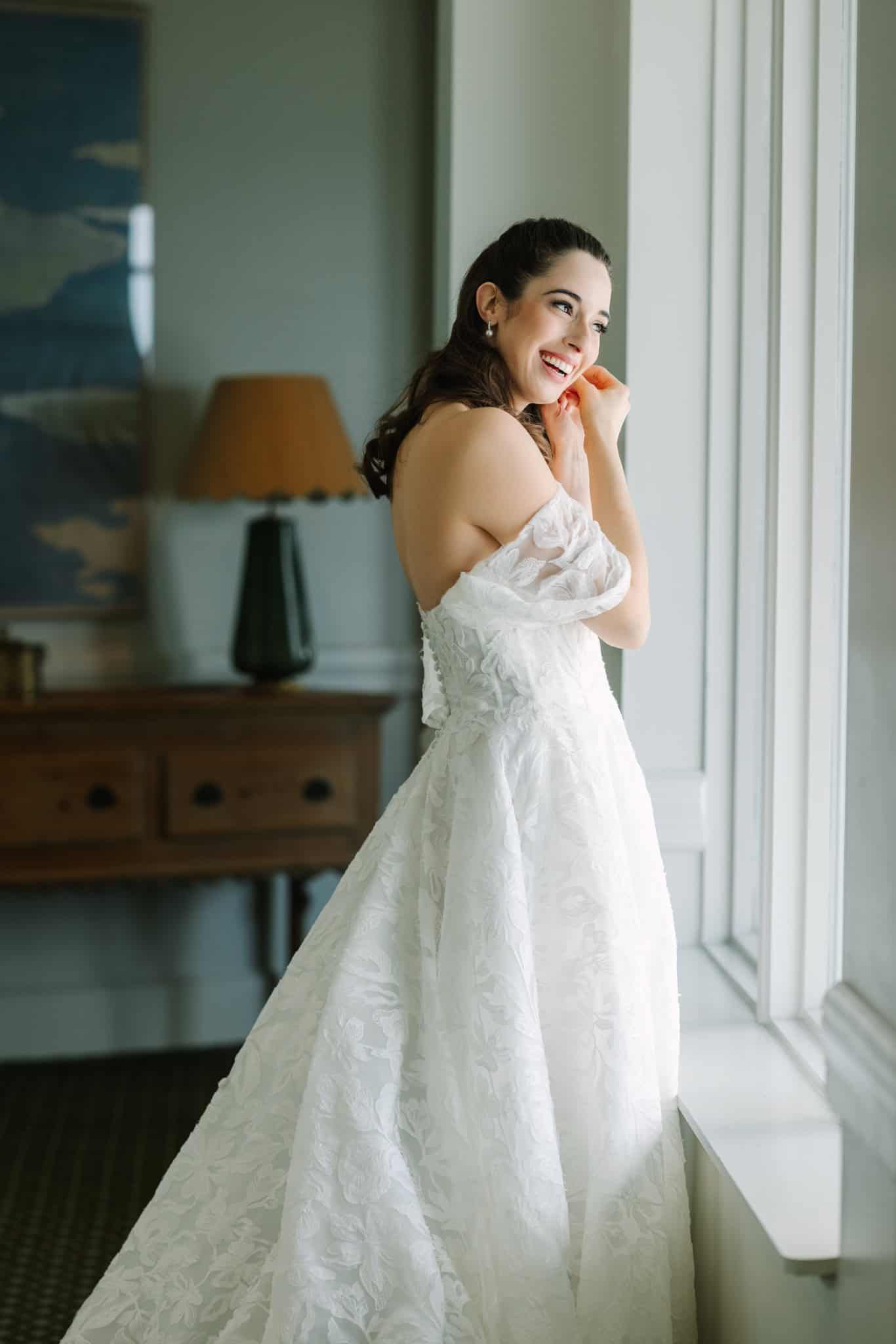 bride looking out the window putting her earrings on