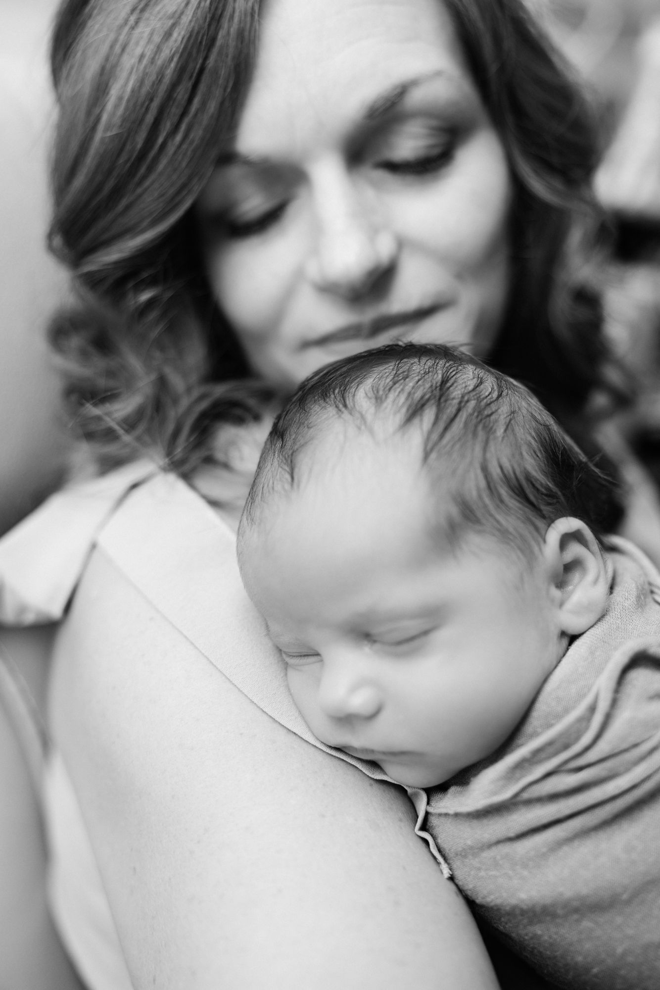 newborn baby snuggling on mothers shoulder in black and white