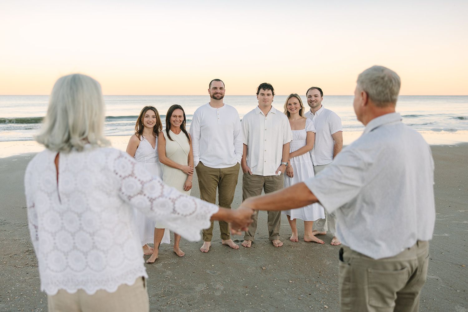 extended family with mom and dad holding hands in the foreground with their kids smiling at sunset by Jacksonville, fl photographer