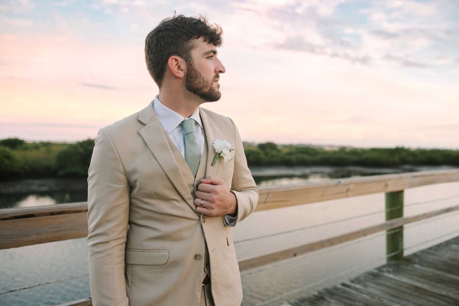 groom holding his lapel and looking off to the right
