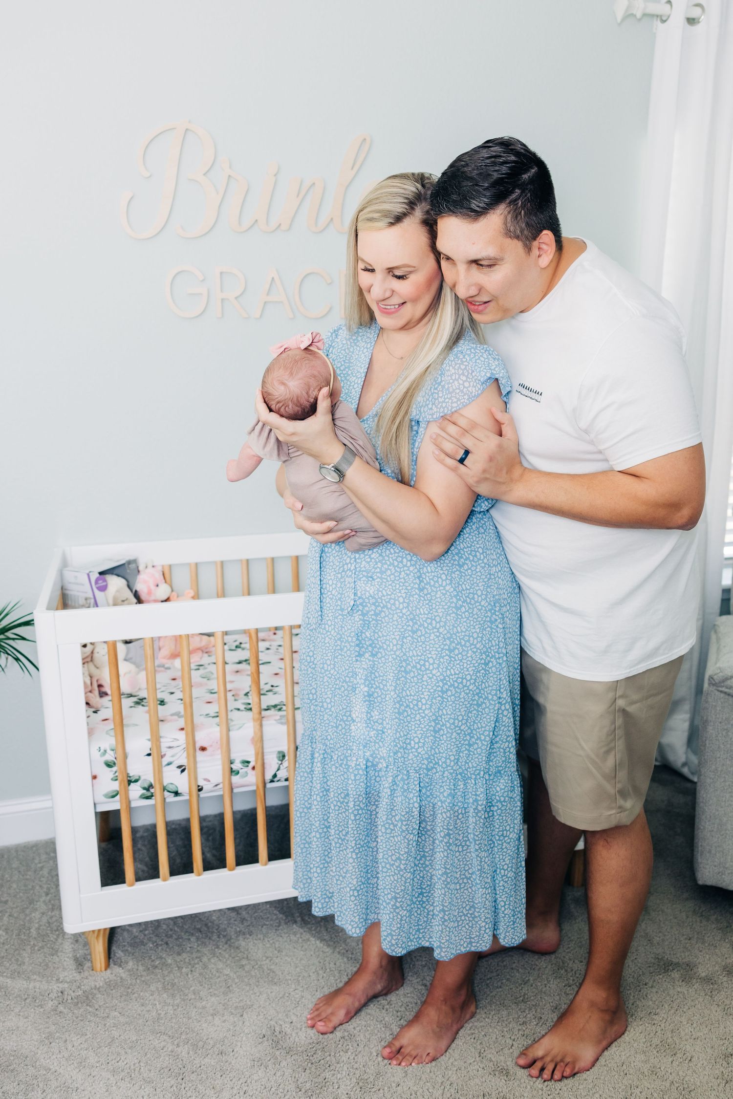 mom and dad standing in front of the crib holding newborn baby